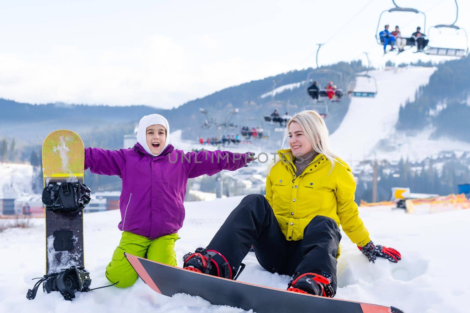 Mother and daughter with snowboards are playing in the snow