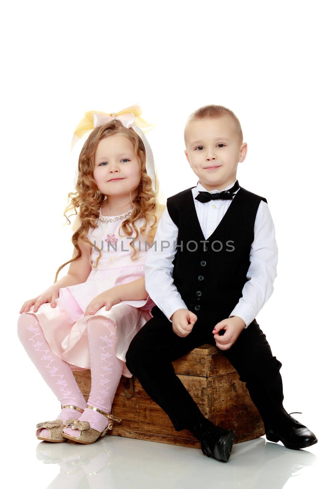 Little boy and girl sitting on the old trunk.Isolated on white background.