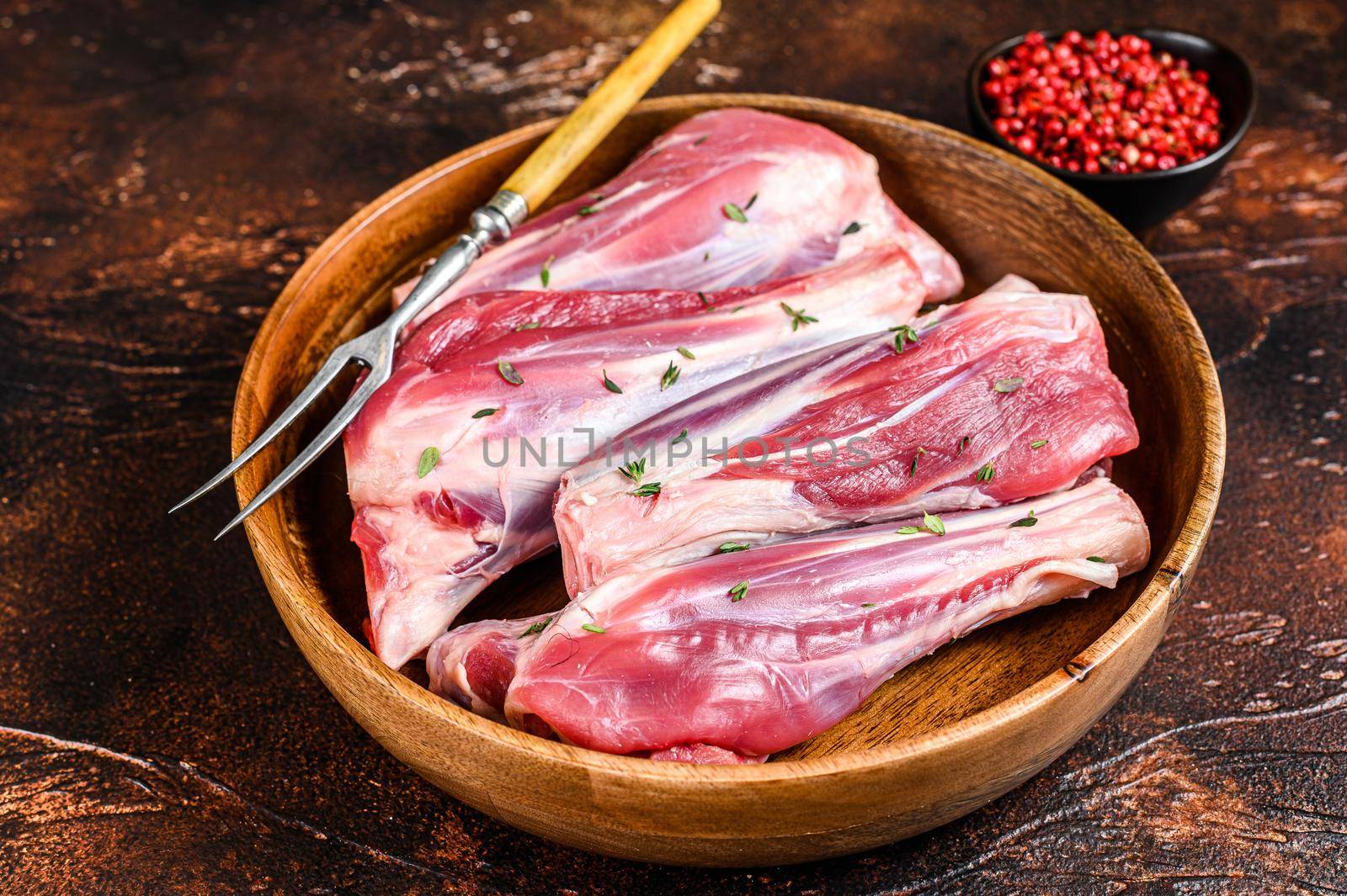 Fresh Raw lamb leg shanks meat in a wooden plate. Dark background. Top view.