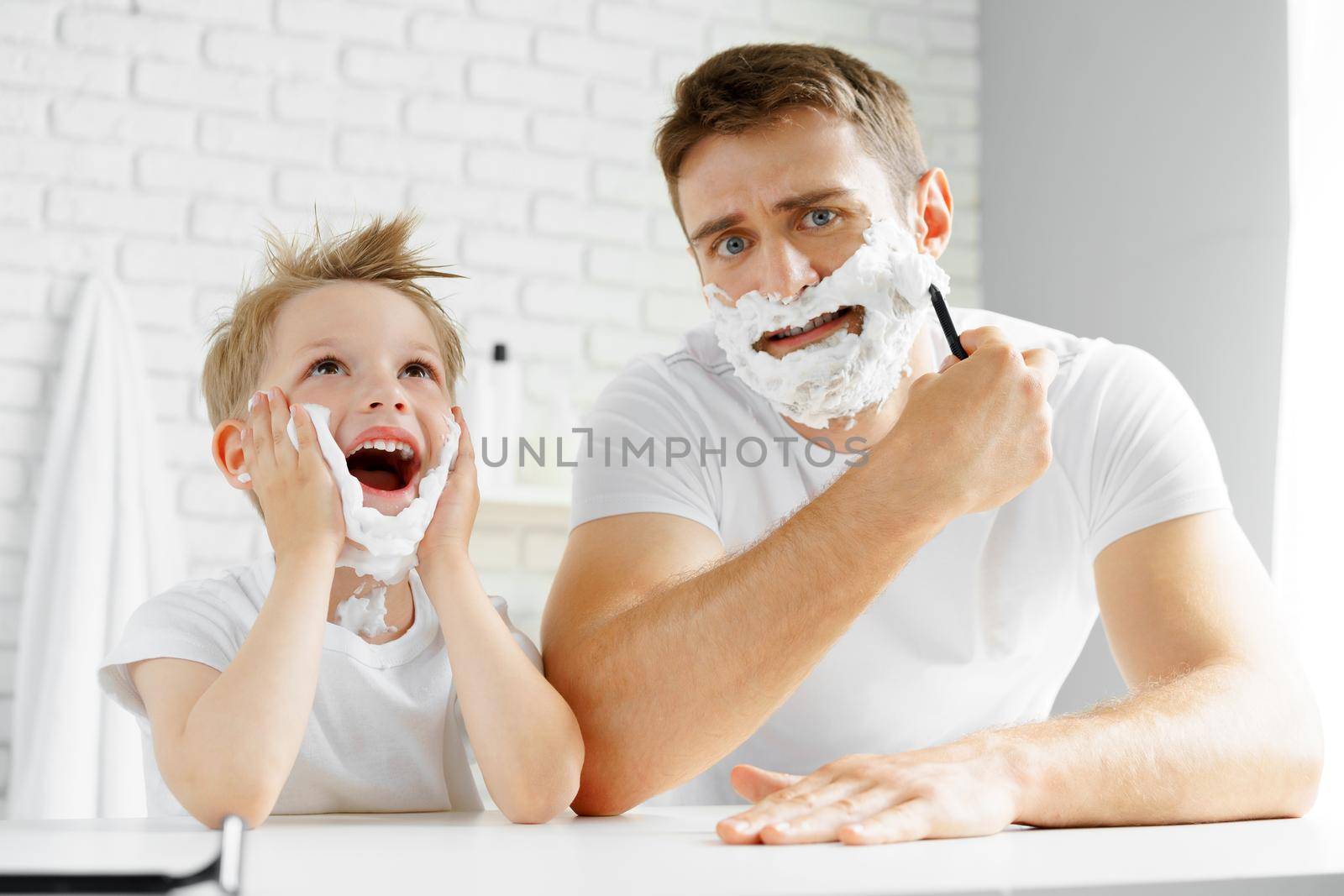 Father and little son having fun with shaving foam in bathroom
