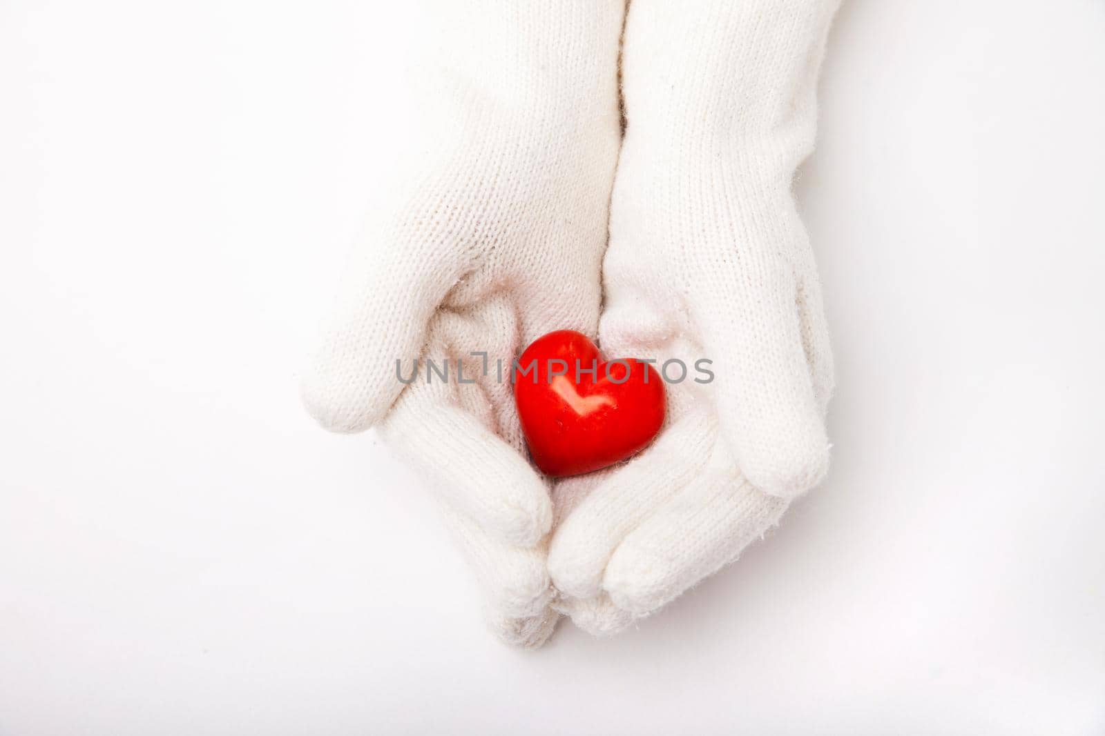 Woman hands in white gloves holding red heart symbol