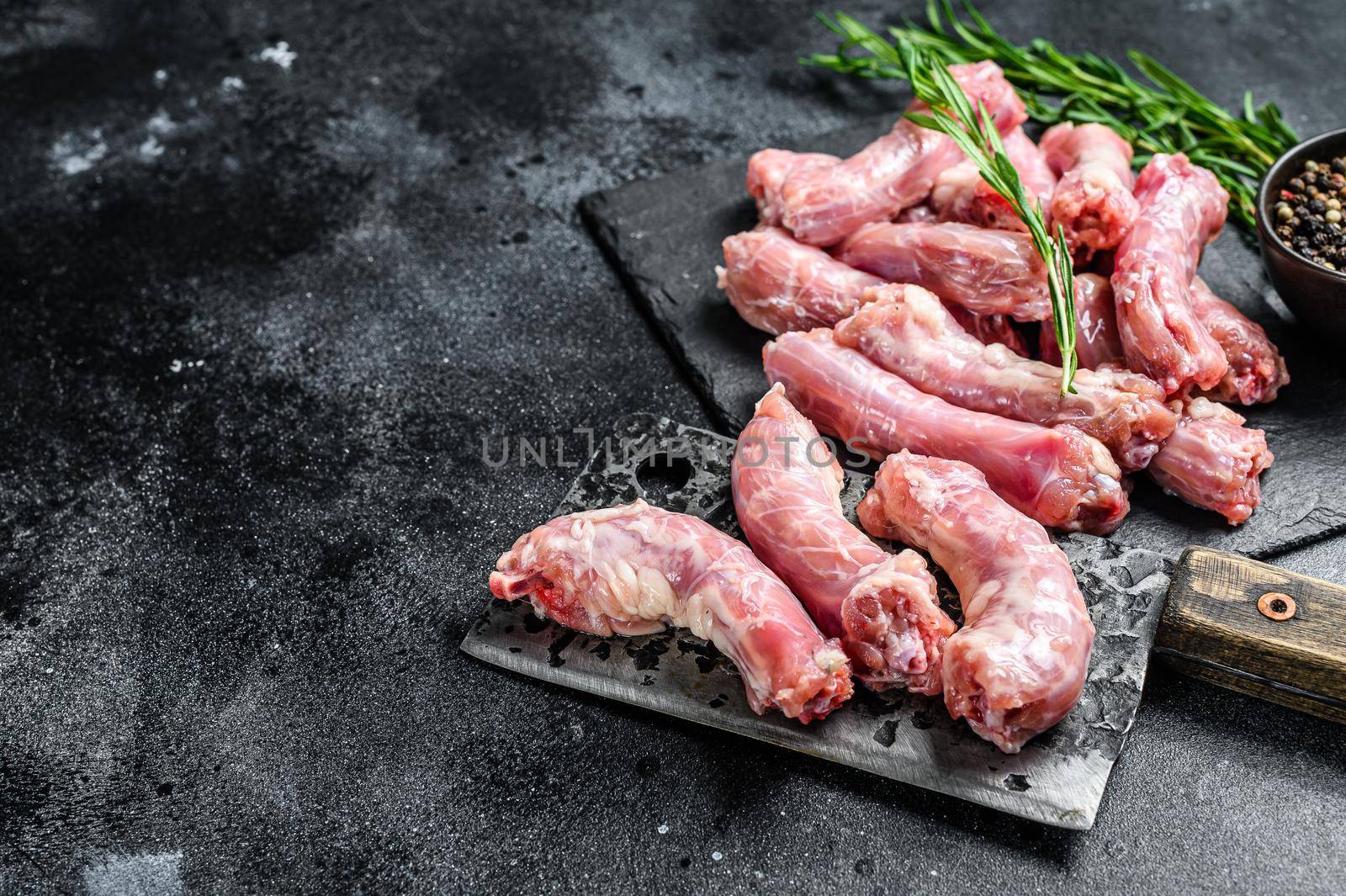 Raw Turkey neck meat on a cutting board. Black background. Top view. Copy space by Composter