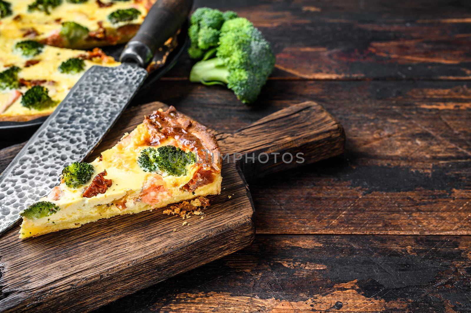 Quiche tart with smoked salmon, broccoli and spinach. Dark wooden background. Top view. Copy space by Composter