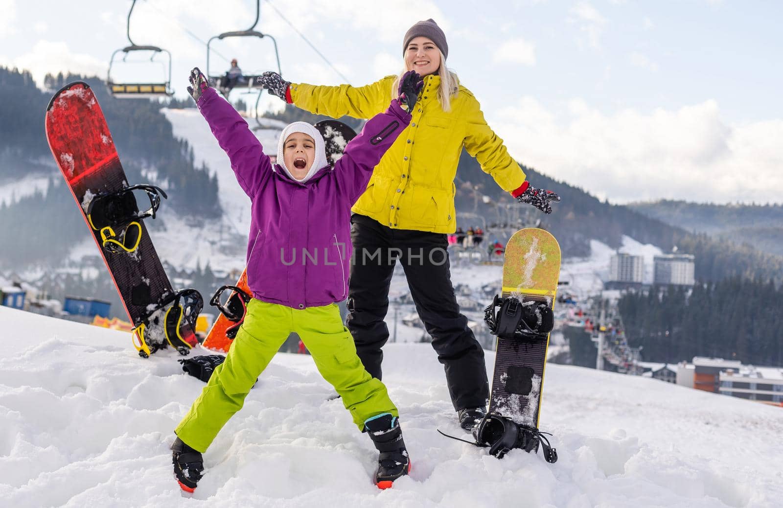 mother and daughter with snowboards at winter resort