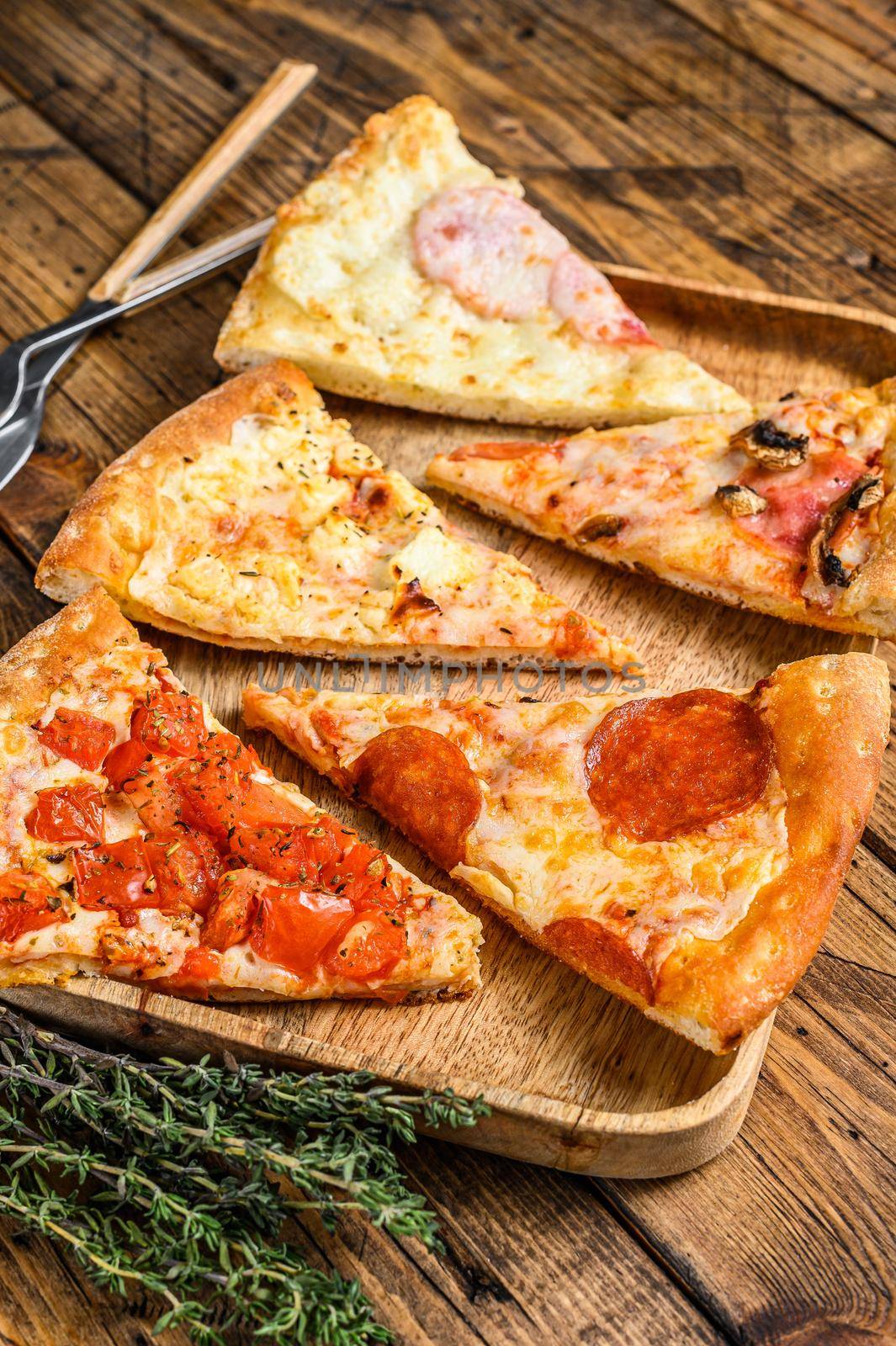 Pieces of different pizza various types. Wooden background. Top view.