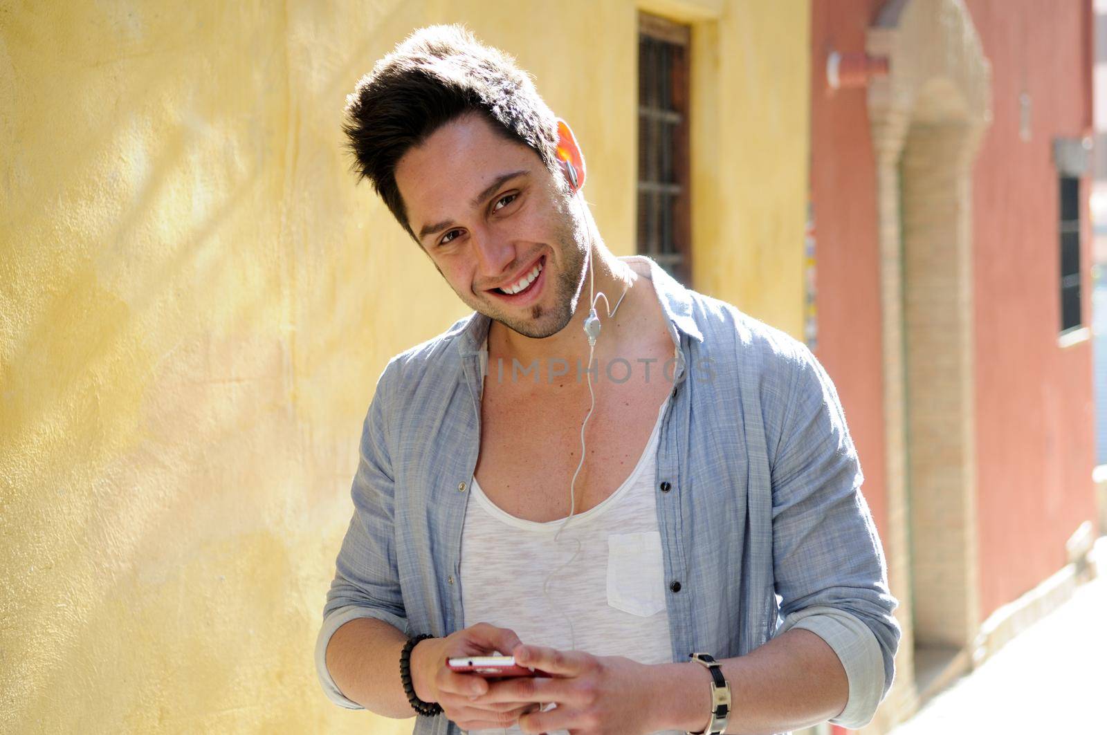 Portrait of handsome man in urban background listening to the music with headphones
