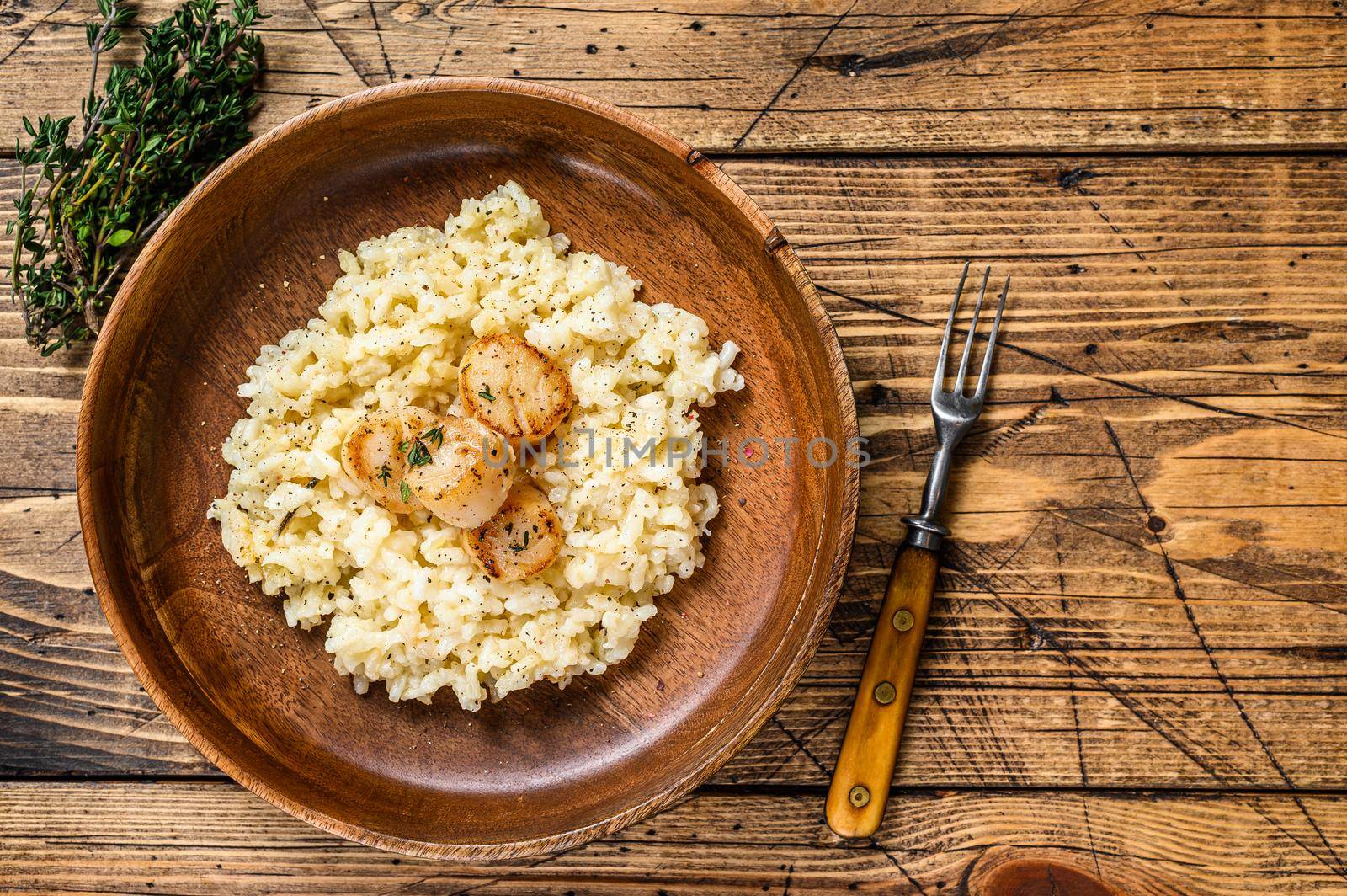 Italian Risotto with Scallops in a pan. wooden background. Top view. Copy space by Composter