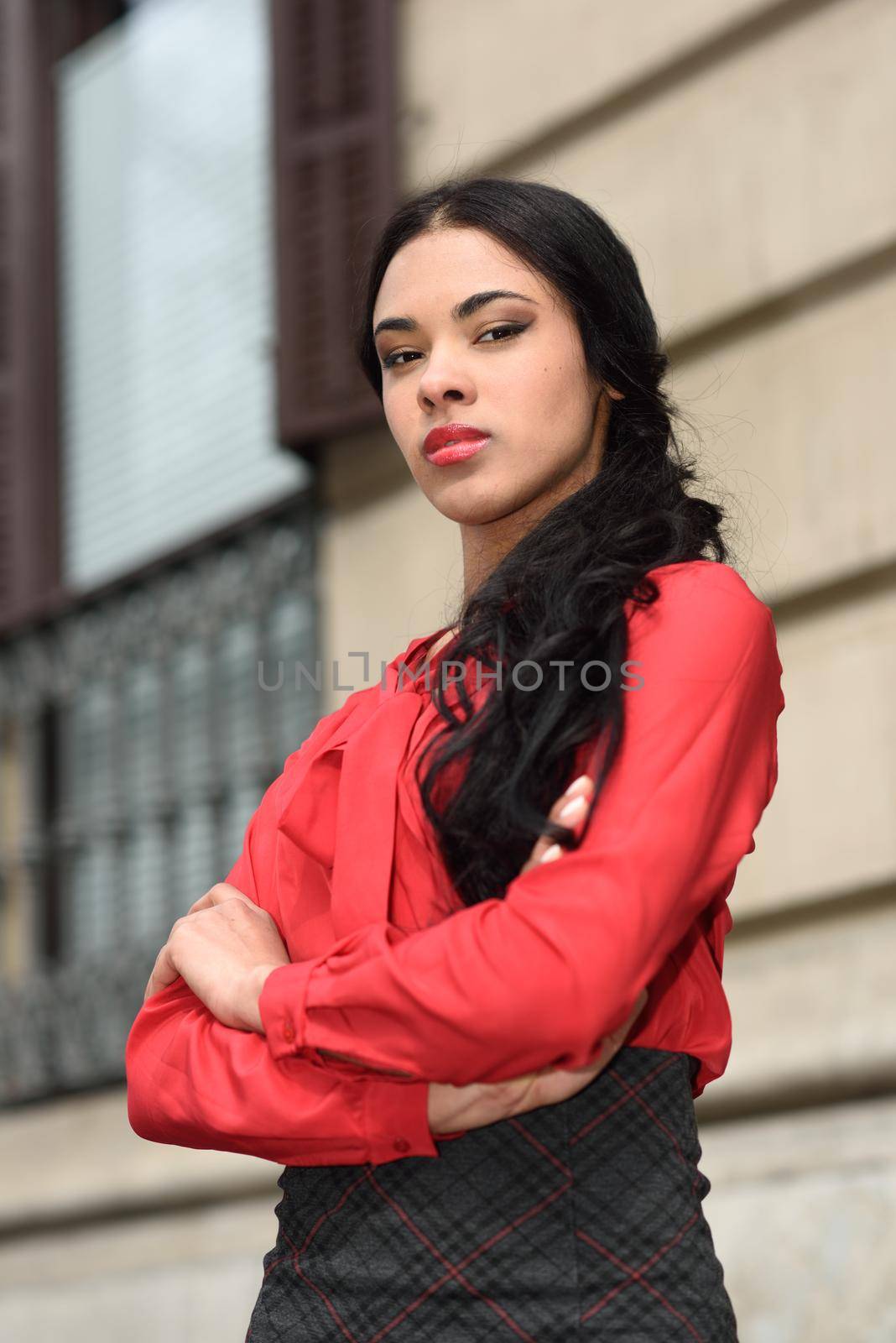 Portrait of hispanic bussinesswoman in urban background wearing red shirt and skirt