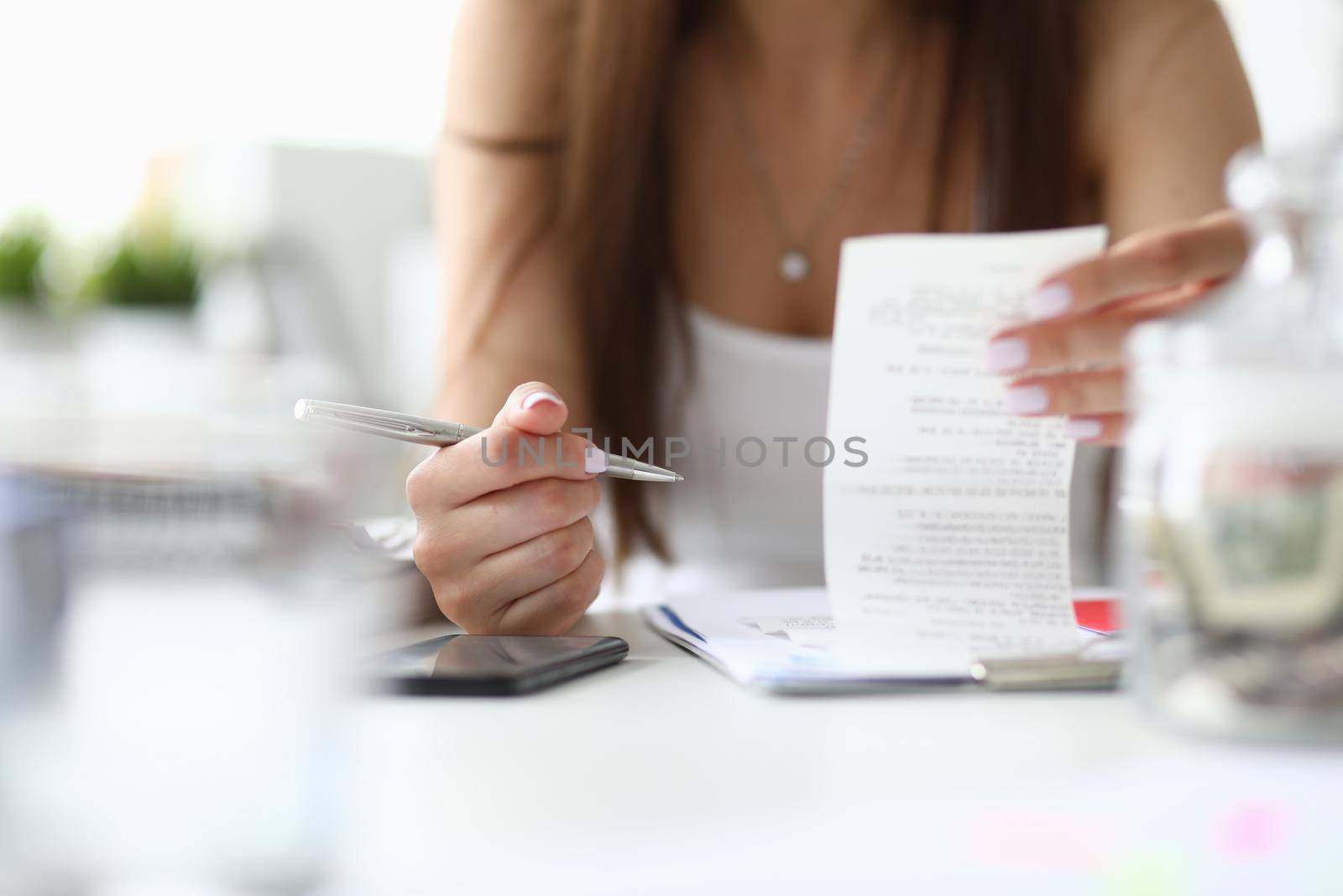 Focus on tender hands of businesswoman sitting indoors with metallic silver pen and important tablet with significant business documents. Office concept. Blurred background