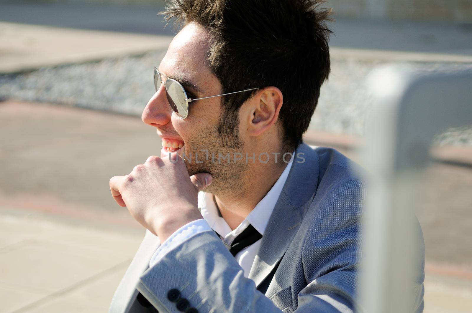 Man dressed in suit and suitcase sitting on the floor in the street