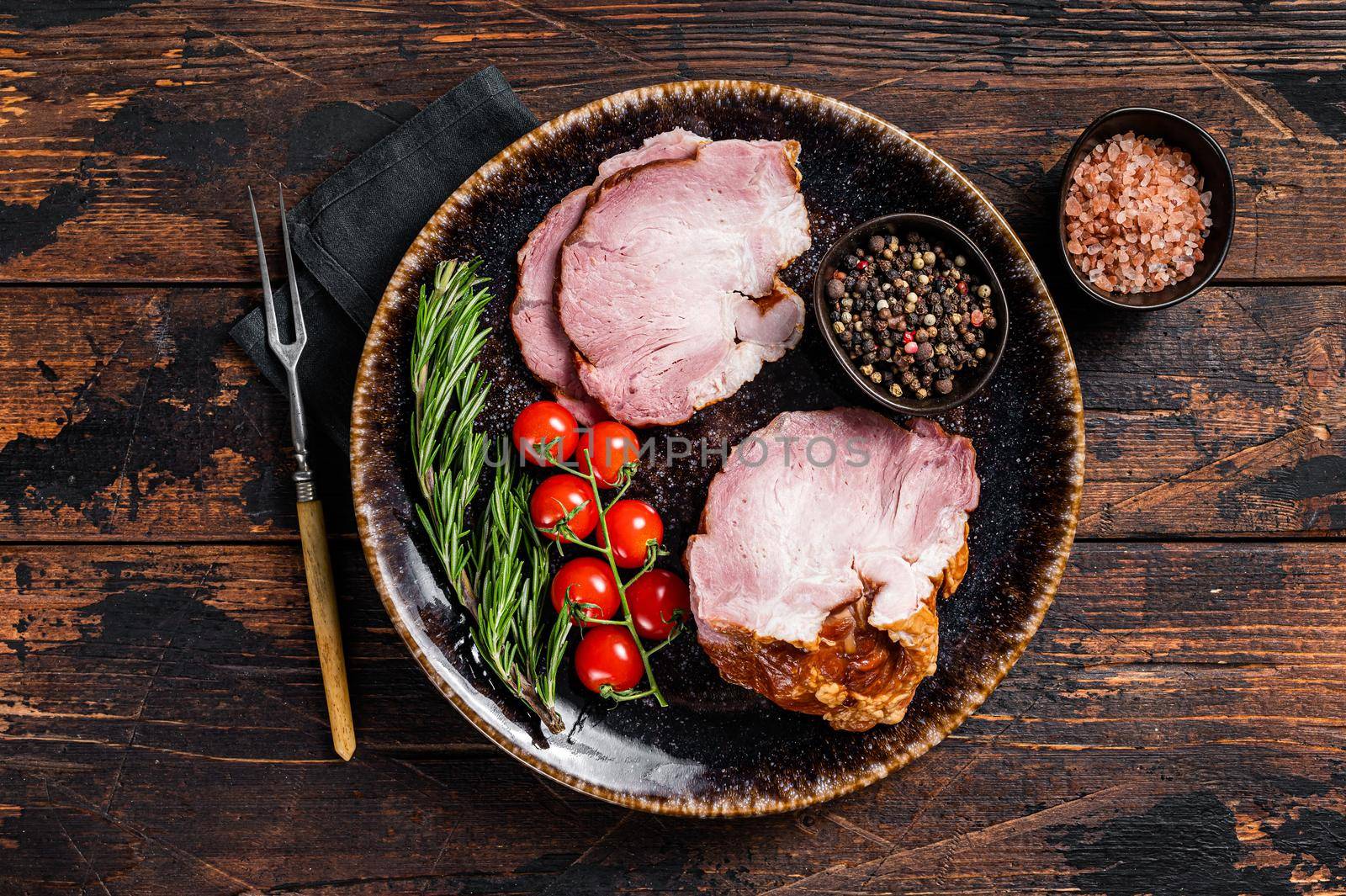 Smoked pork meat - gammon with herbs on rustic plate. Wooden background. Top view.
