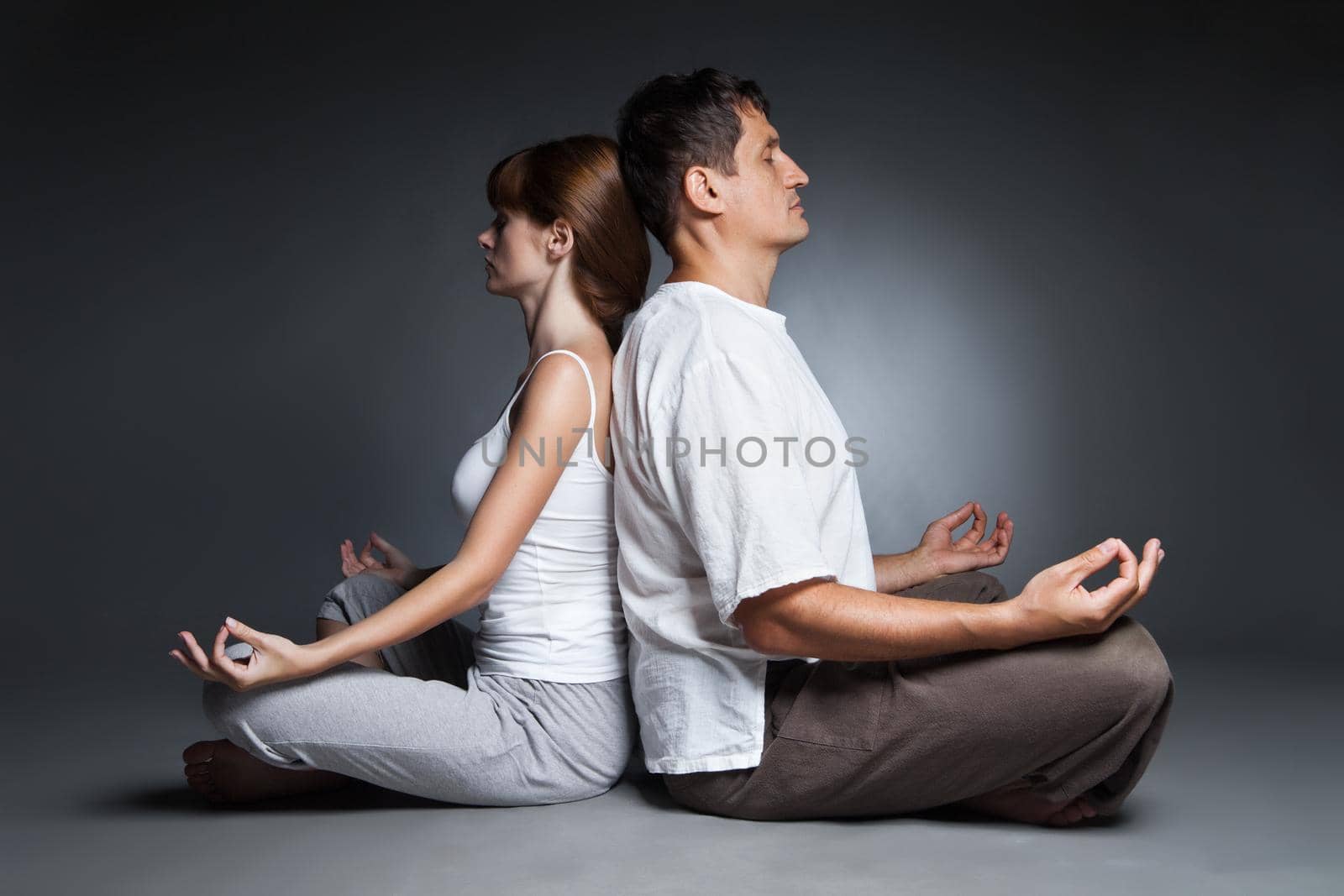 Healthy couple in yoga position on dark by Julenochek