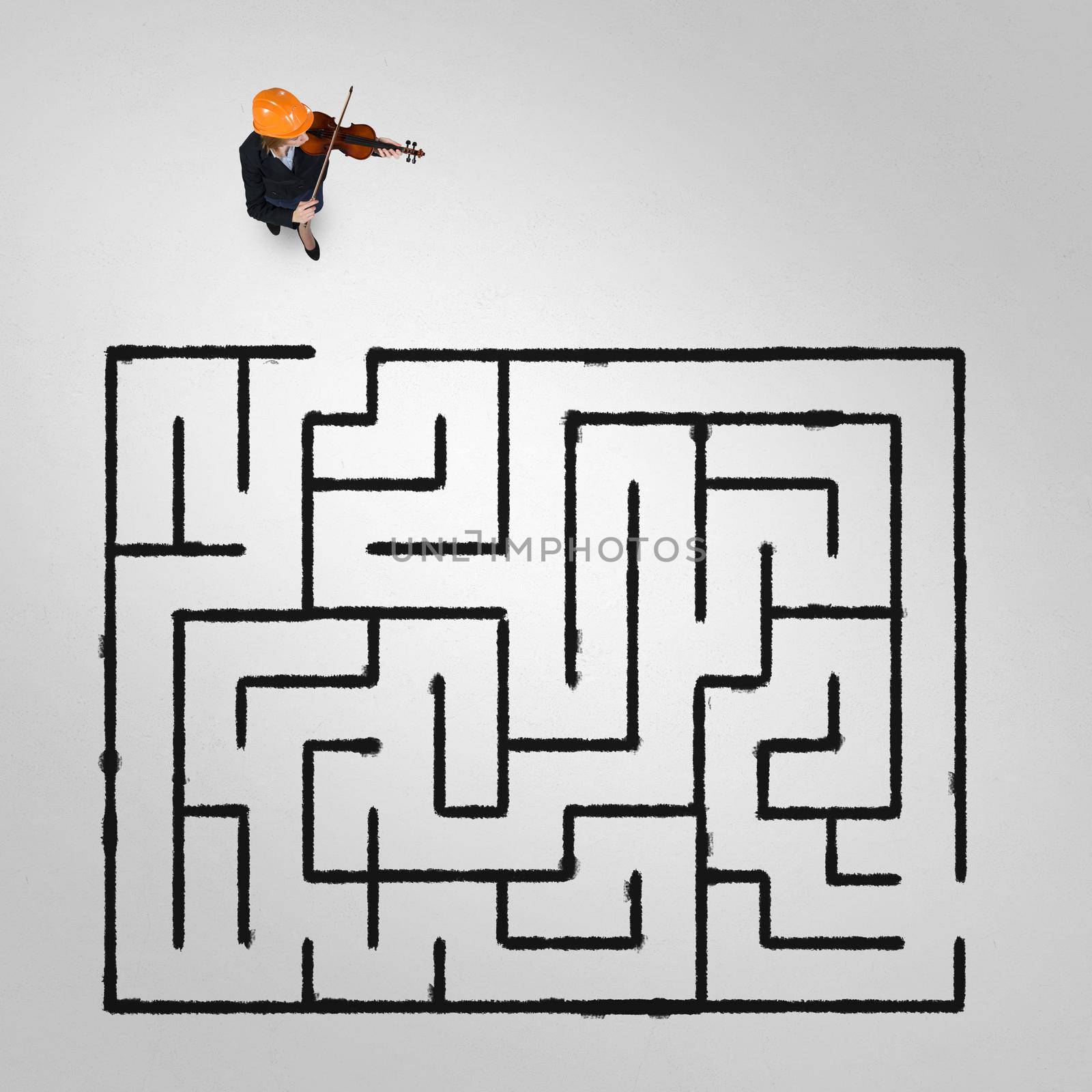 Top view of businesswoman playing violin and drawn labyrinth on floor