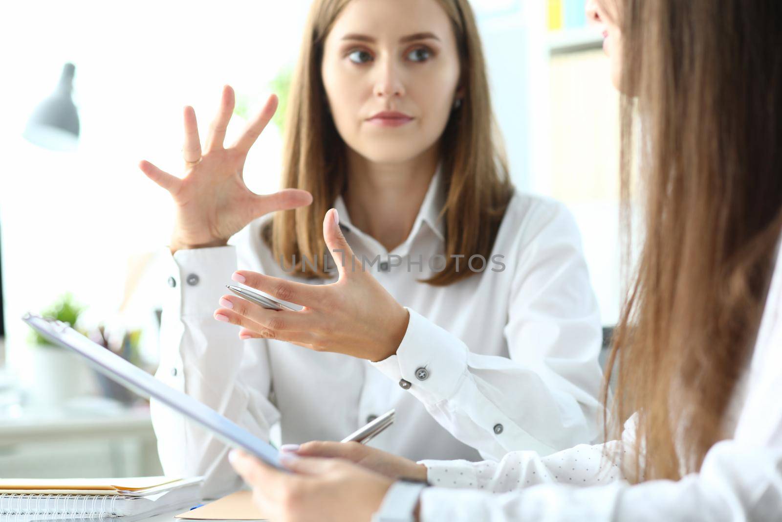 Portrait of concerned businesswoman sitting in modern workplace and discussing important topic. Pretty business lady working on project. Accounting office concept