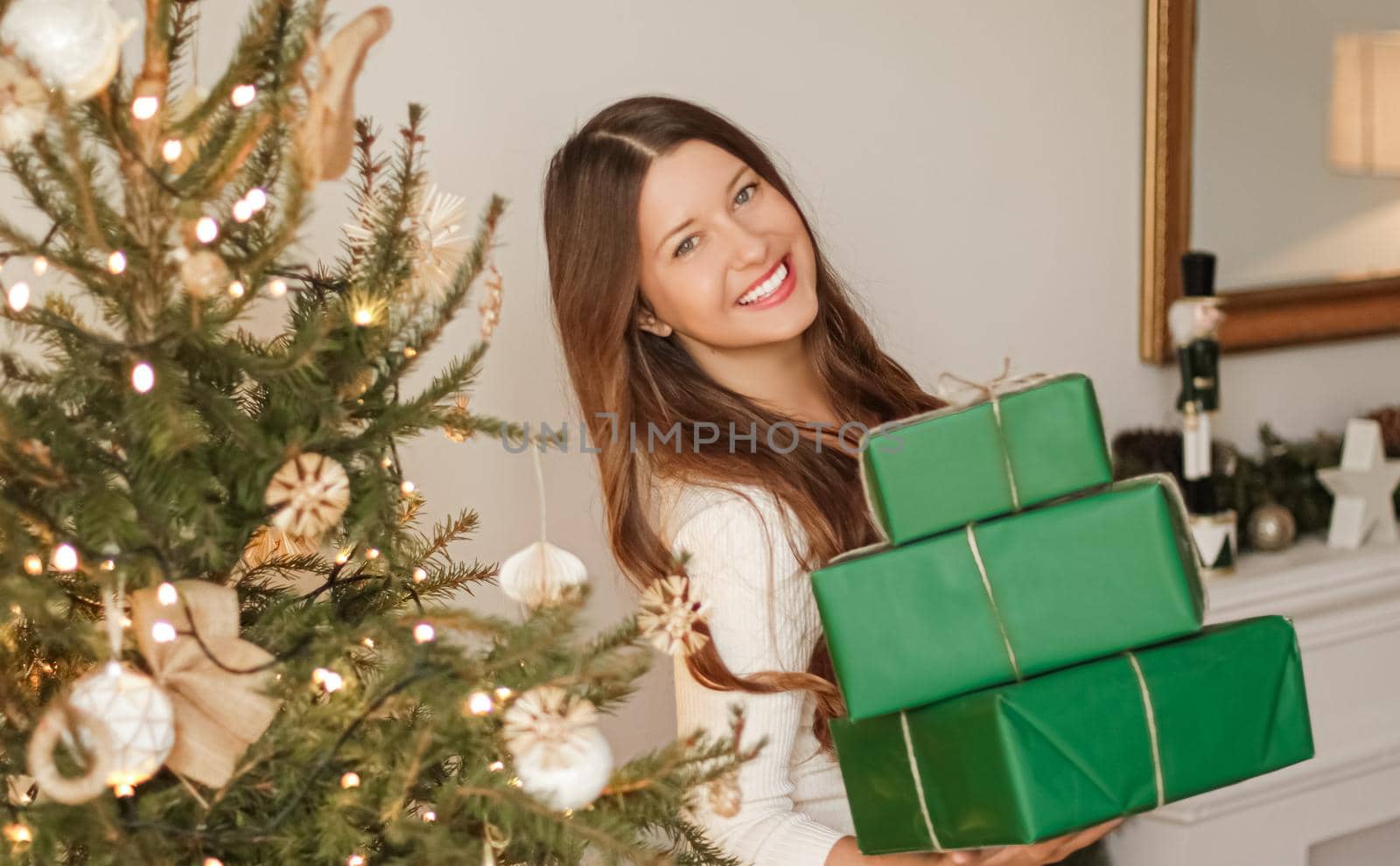 Christmas holiday and sustainable gifts concept. Happy smiling woman holding wrapped presents with eco-friendly green wrapping paper.