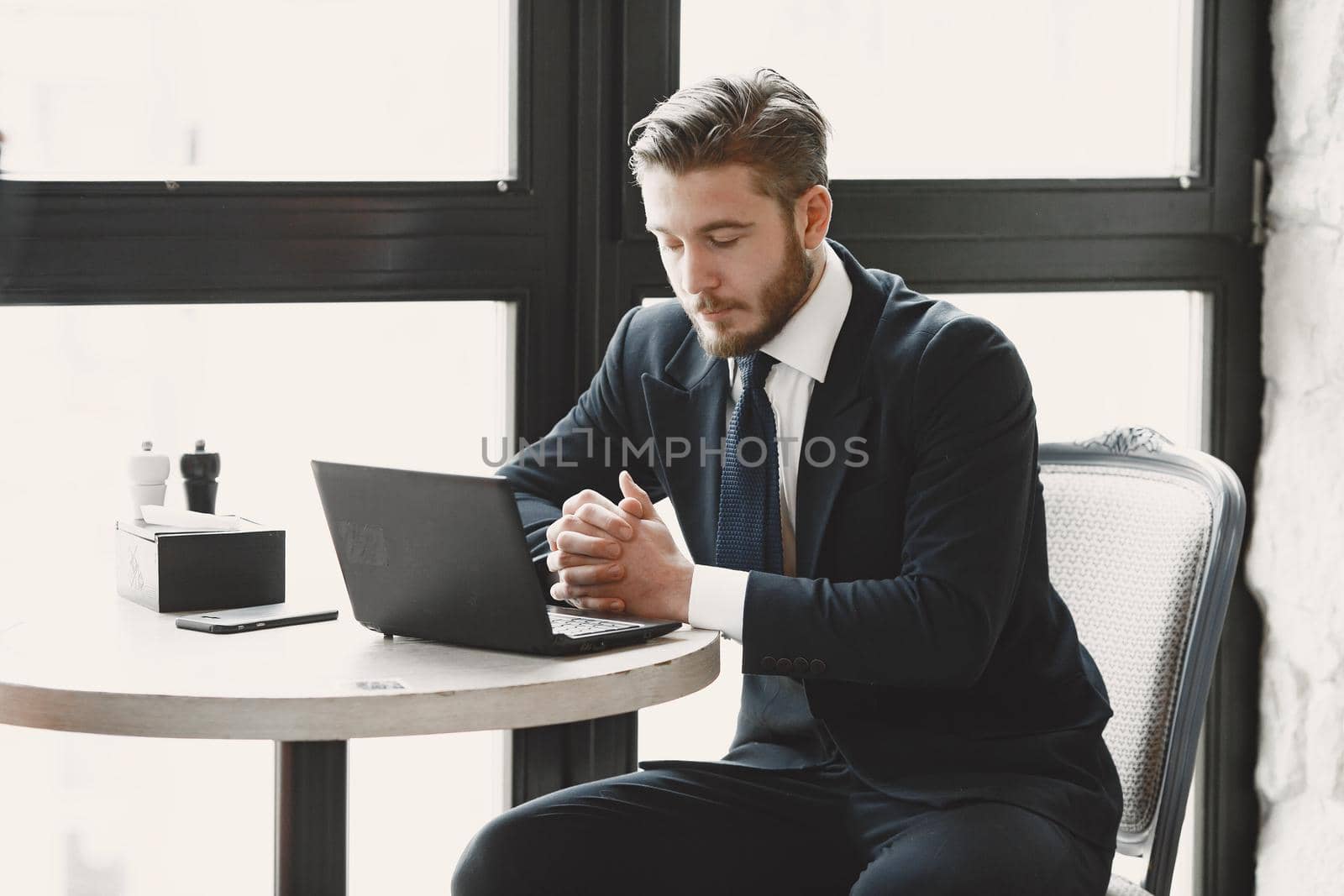 Guy in a black suit. Male at the restaurant. Man with a computer.