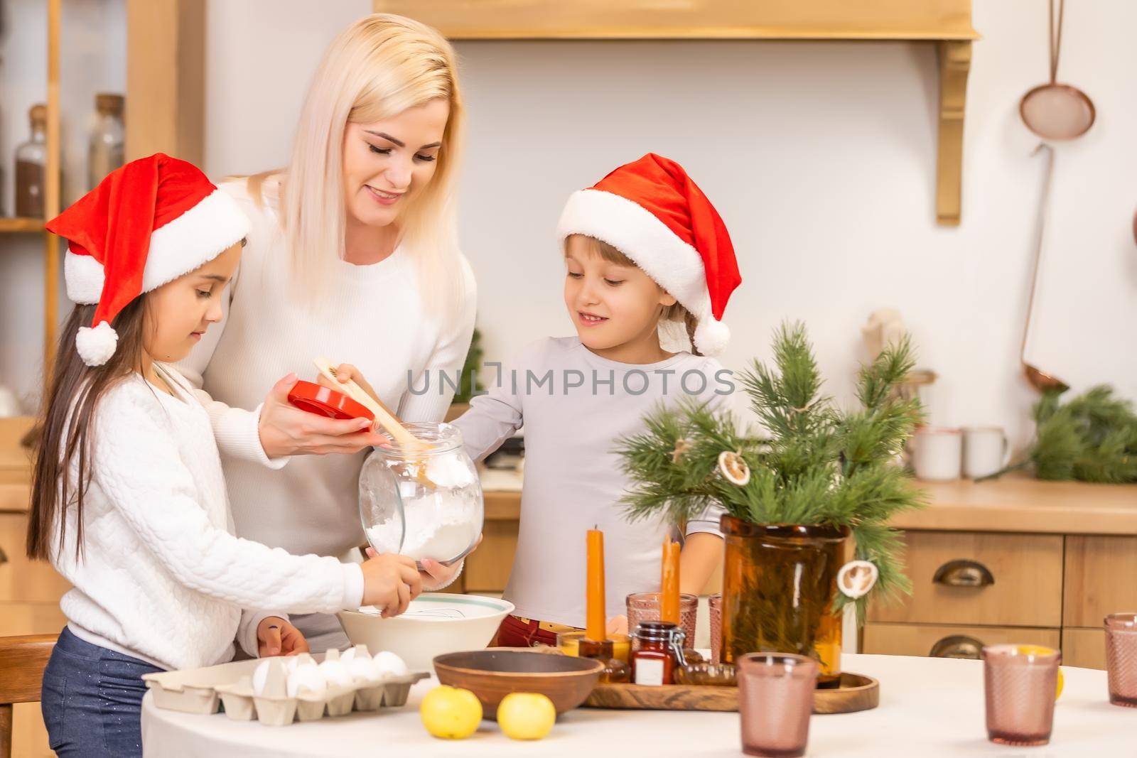 Two girls dressed in red hats are preparing cookies, gingerbread for the New Year holiday, Christmas. Cut out cookies.
