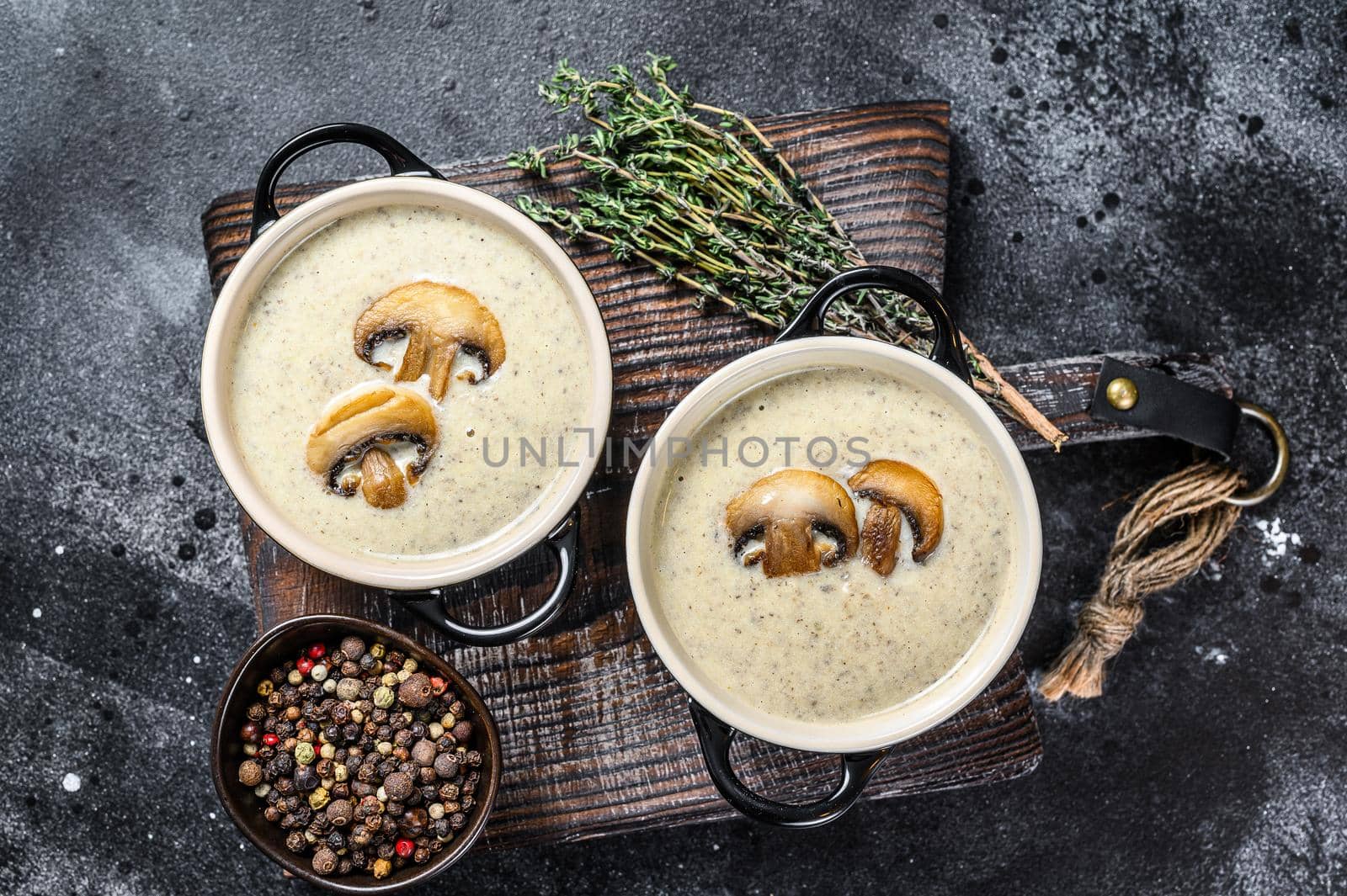 Champignon Mushroom cream soup with herbs in a bowl. Black background. Top view by Composter