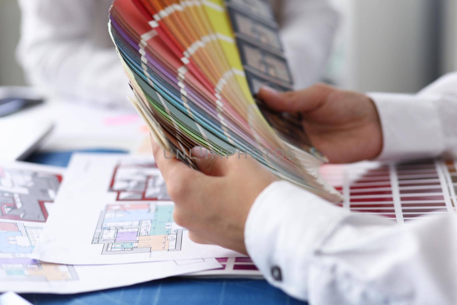 Focus on arms of hardworking businesswoman holding multicolored palette and thinking about important business project at workplace. Creative office concept. Blurred background