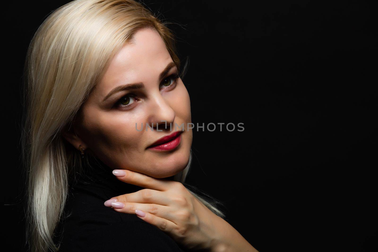 Close-up portrait of beautiful model with long blond hair on black background