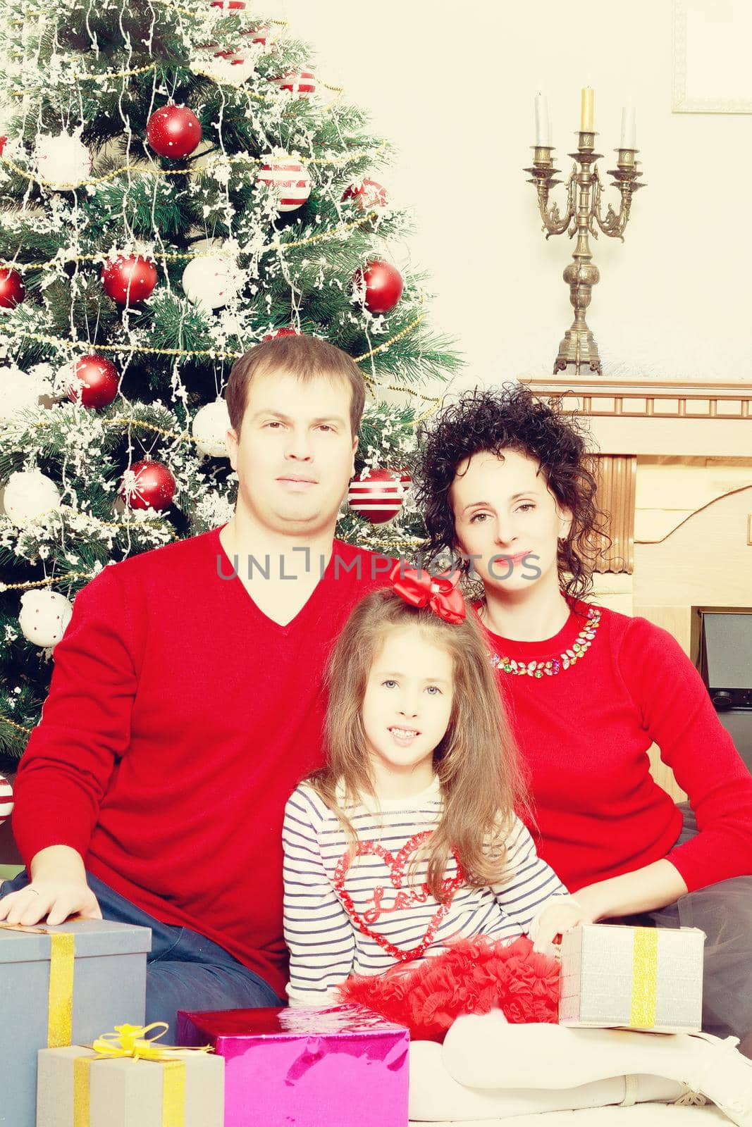 Happy parents with little daughter in a relaxed family atmosphere in the New year.Around the Christmas tree.Creative toning of a photograph.