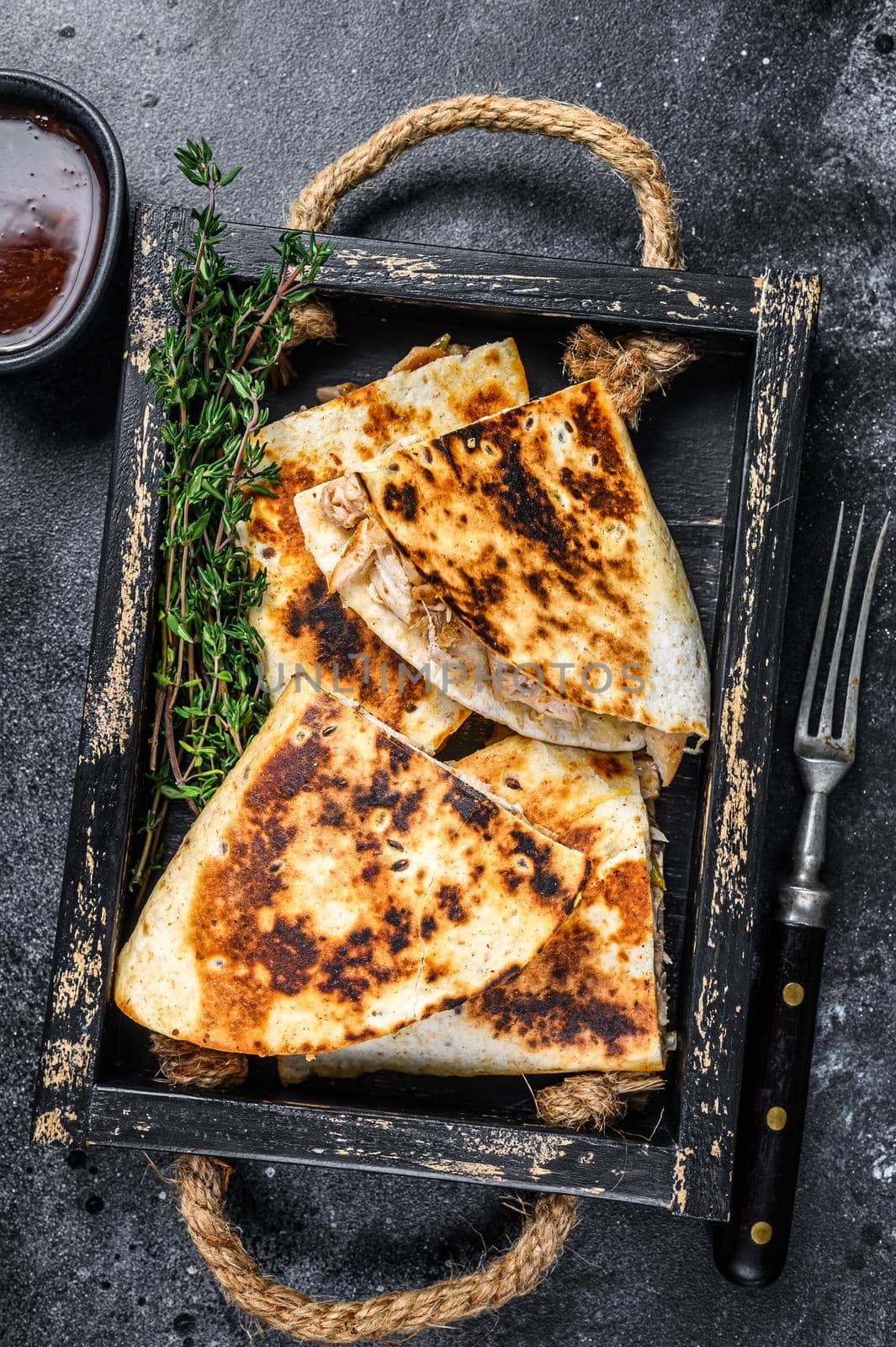 Mexican quesadilla with chicken, tomato, corn and cheese. Black background. Top view.