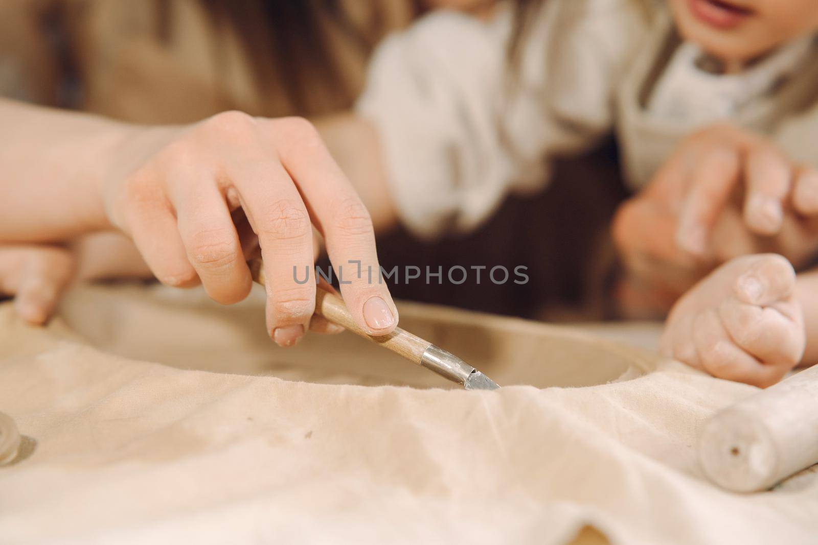 Woman and girl kneading clay. Family make art product at table in pottery workshop. Mother with daughter.