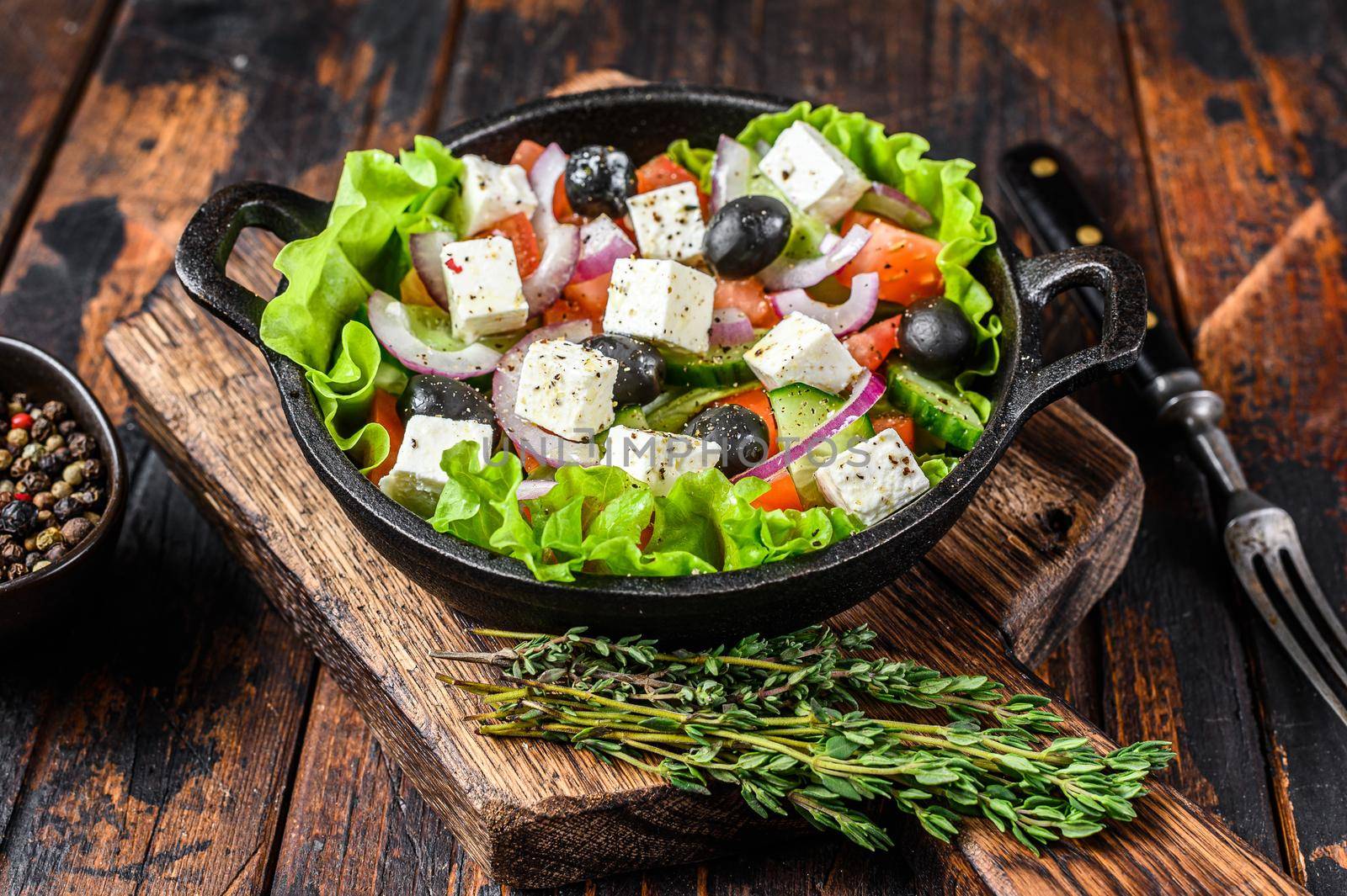 Greek salad with fresh vegetables and feta cheese in a pan. Dark Wooden background. Top view.