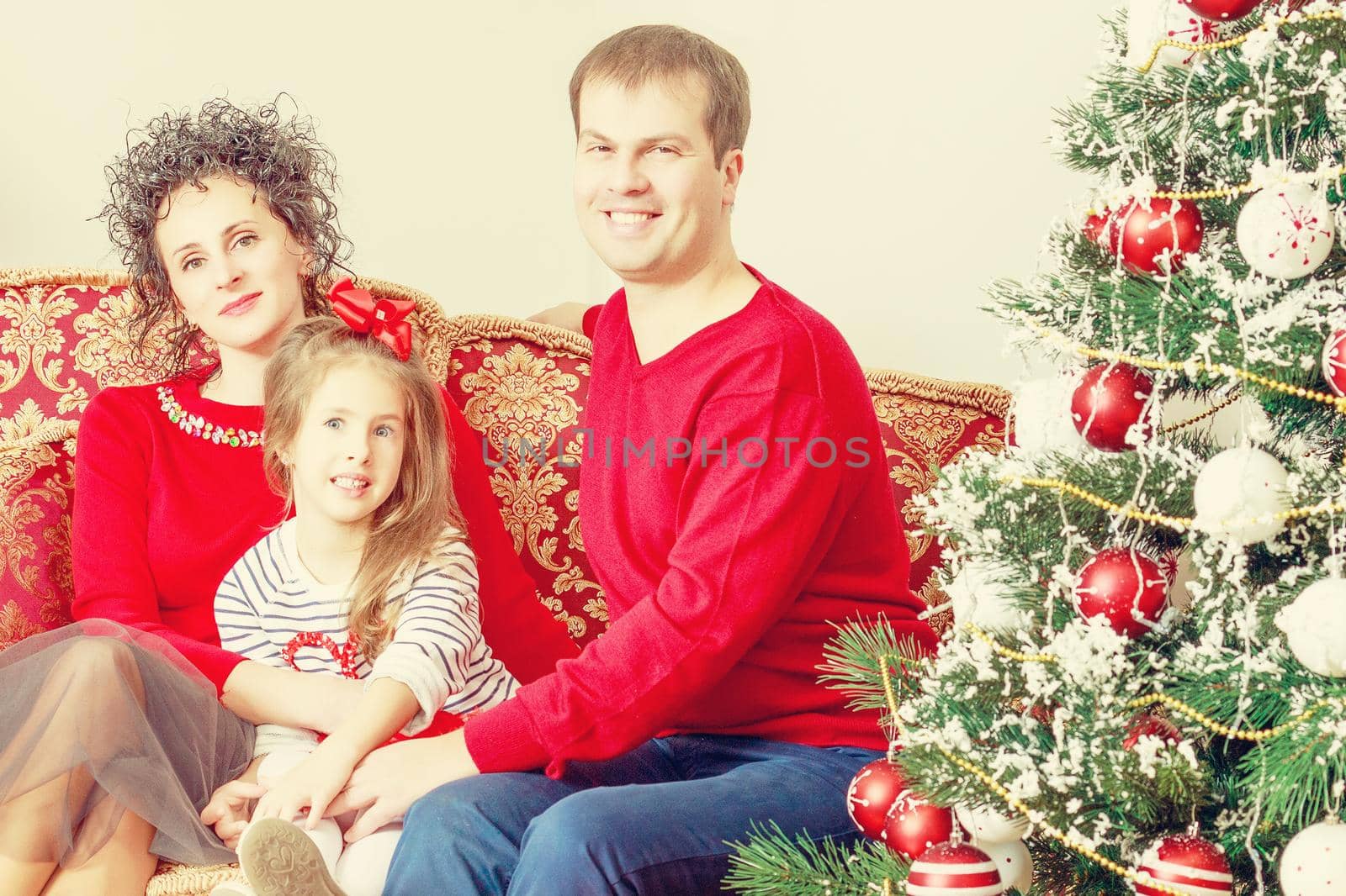 Happy parents with little daughter in a relaxed family atmosphere in the New year.Around the Christmas tree.Creative toning of a photograph.