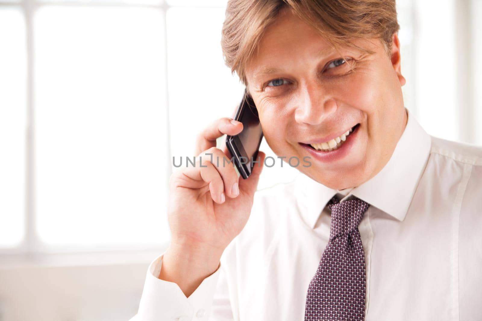 Close up of a laughing businessman on the phone in his office