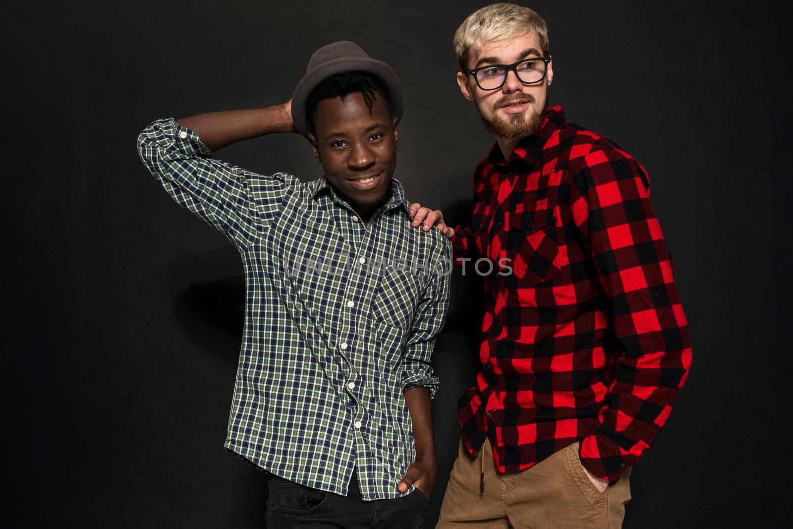 Studio lifestyle portrait of two best friends hipster boys going crazy and having great time together. On black background. by nazarovsergey