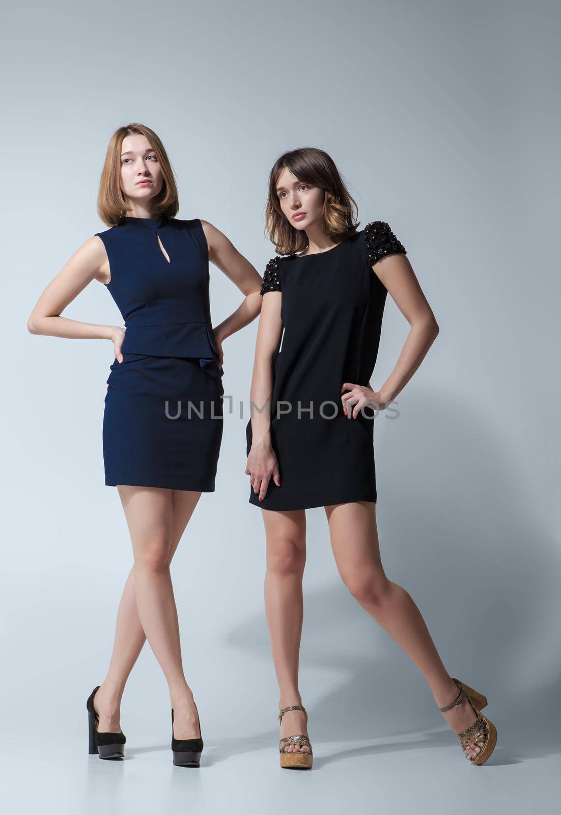 Two beautiful woman posing in a fancy dresses. Studio shooting