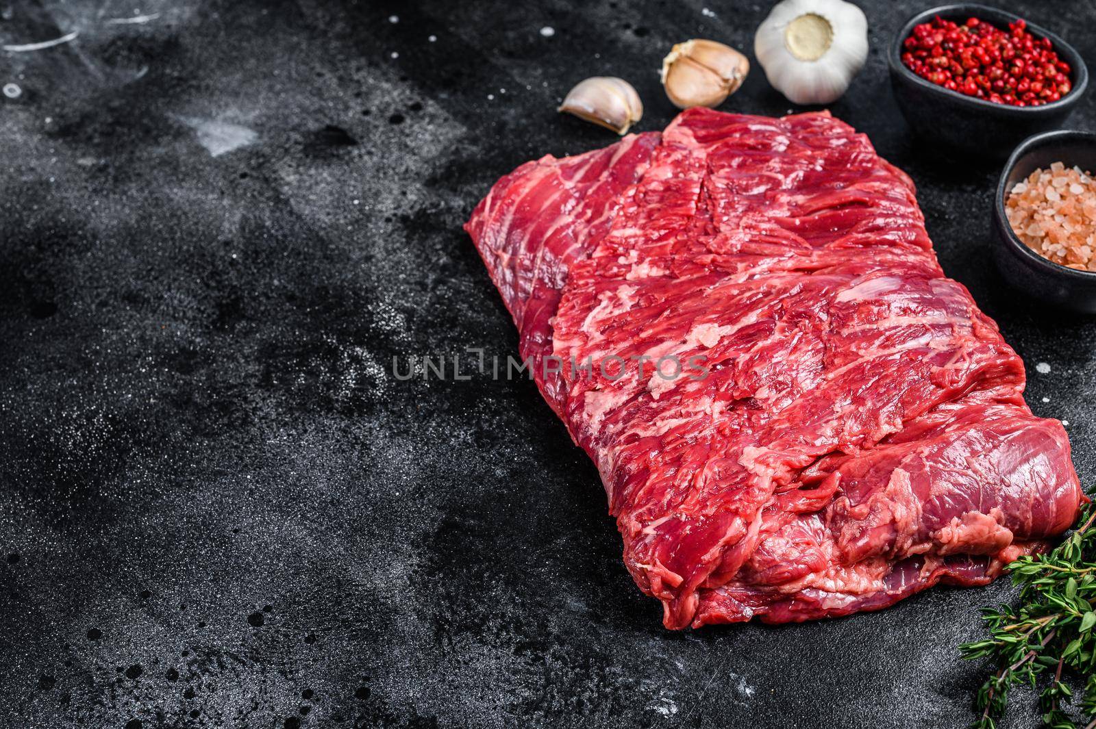 Raw fresh marble beef brisket meat with herbs. Black background. Top view. Copy space by Composter