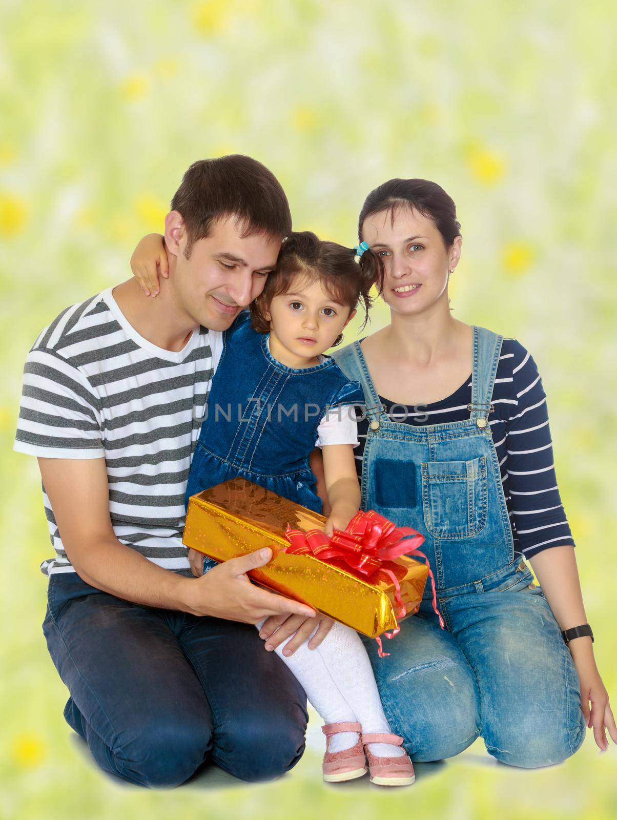 Happy young family with little daughter cuddling together in celebration of Christmas. white green blurred background.