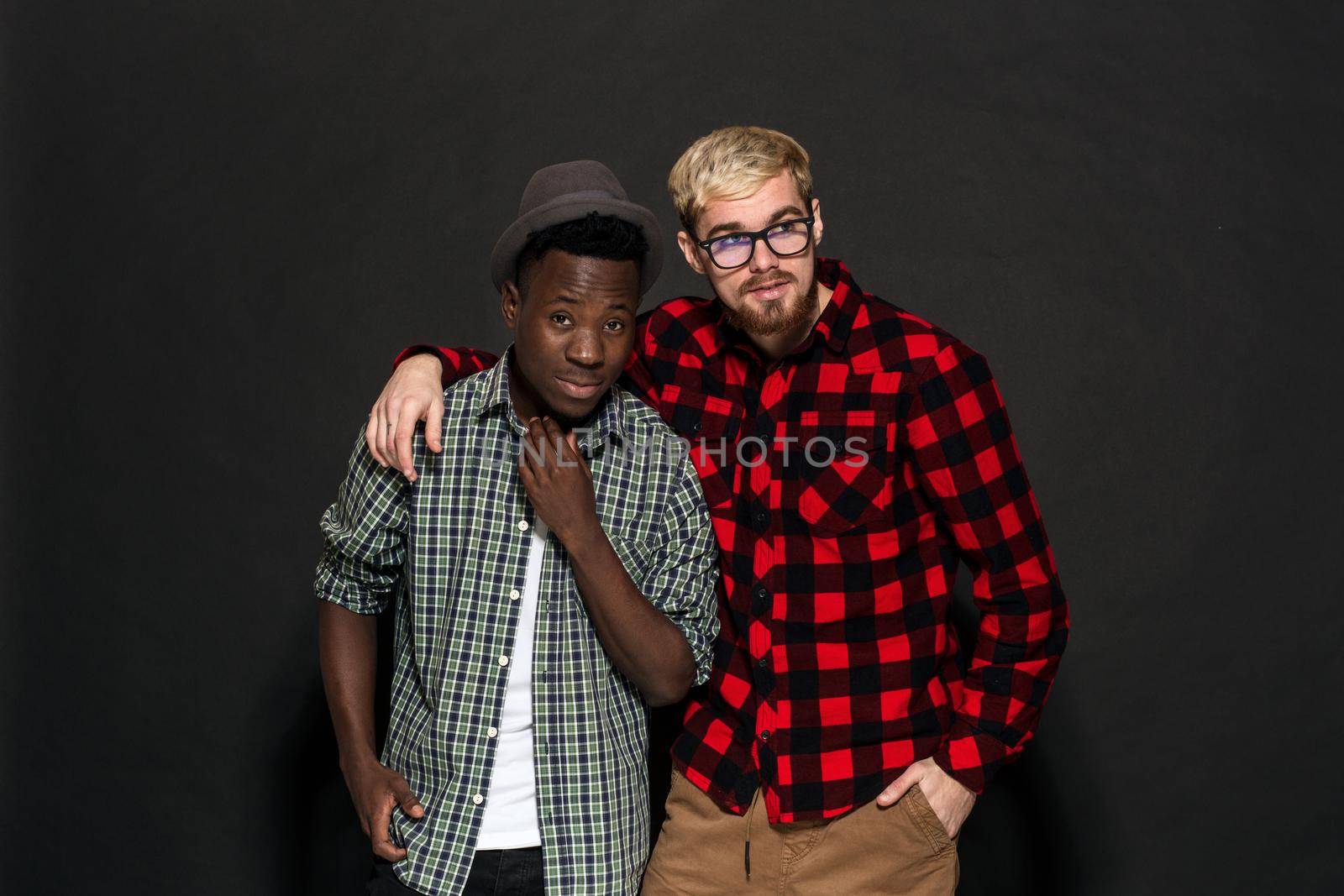 Studio lifestyle portrait of two best friends hipster boys going crazy and having great time together. On black background. Belt portrait