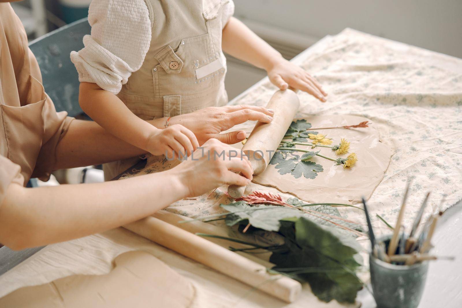 Woman and girl kneading clay. Family make art product at table in pottery workshop. Mother with daughter.