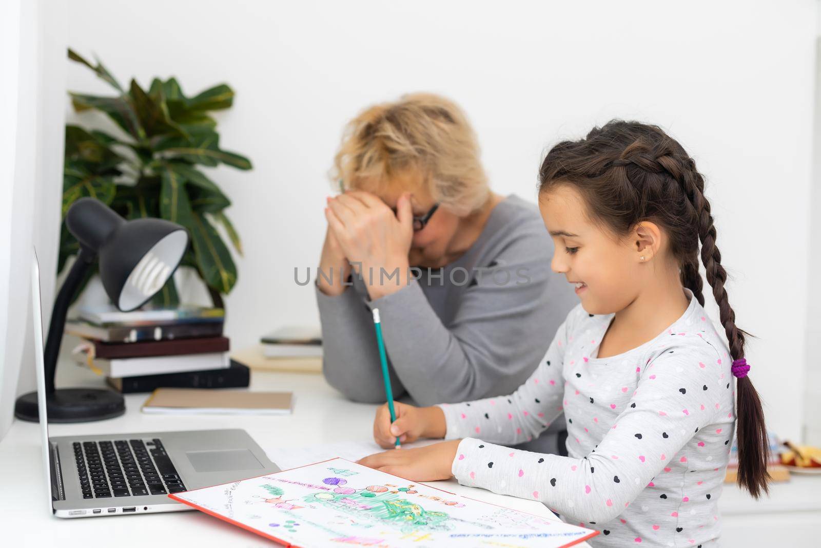 Helpful granny. Helpful loving granny assisting her cute granddaughter making homework by Andelov13