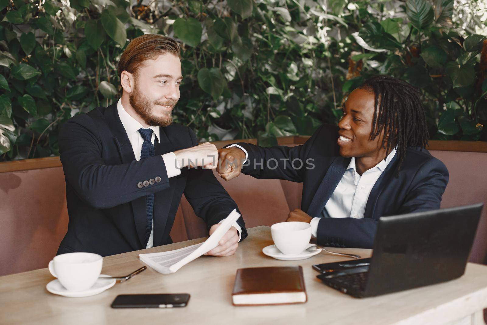 African man. Guy in a black suit. Mixed people have a metting at the cafe.