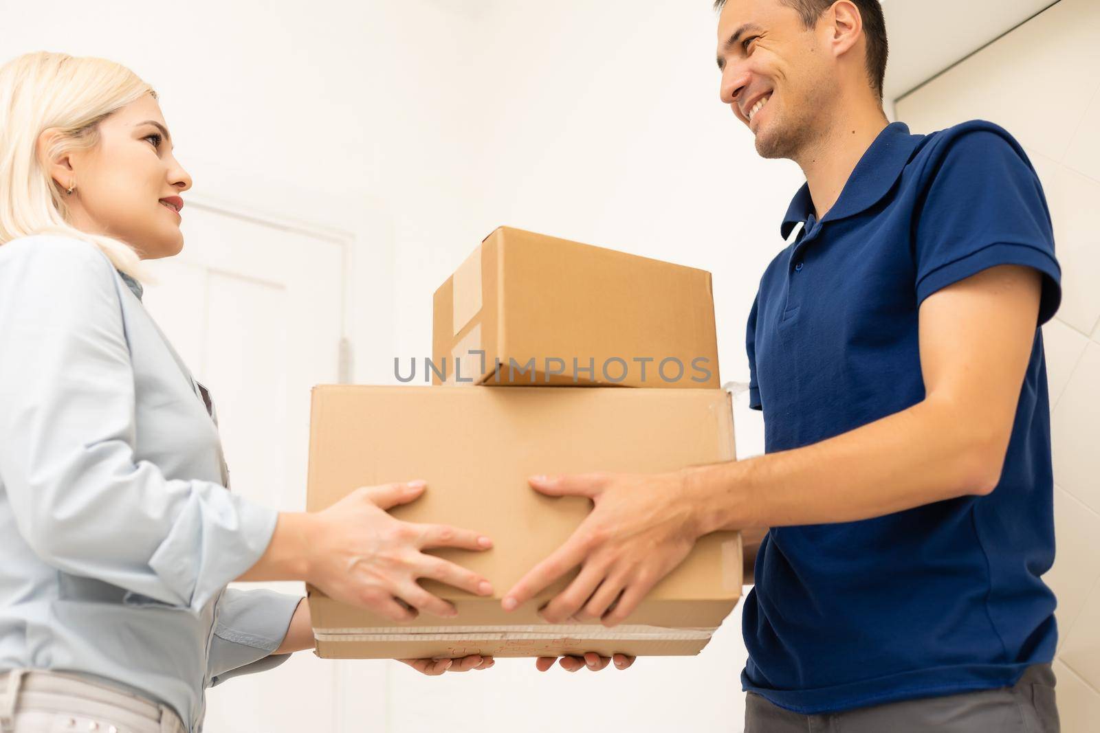 Smiling delivery man giving boxes to woman customer at home for online shopping service concept by Andelov13