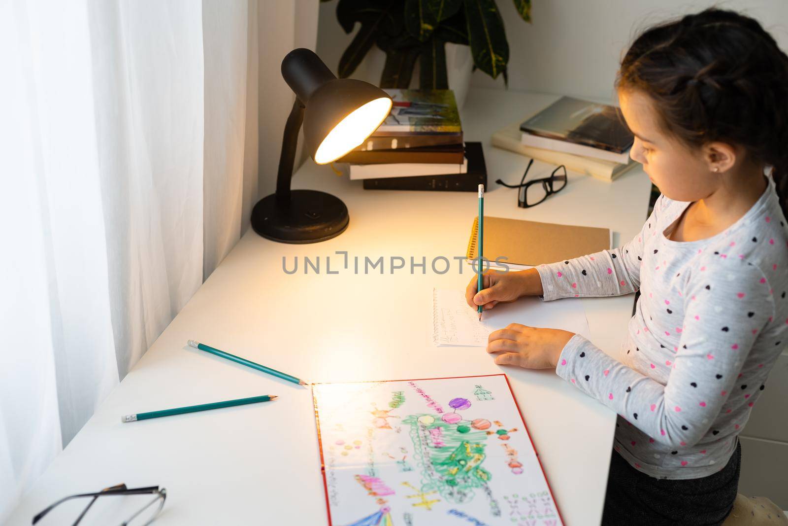 children, education and learning concept - student girl with book writing to notebook at home