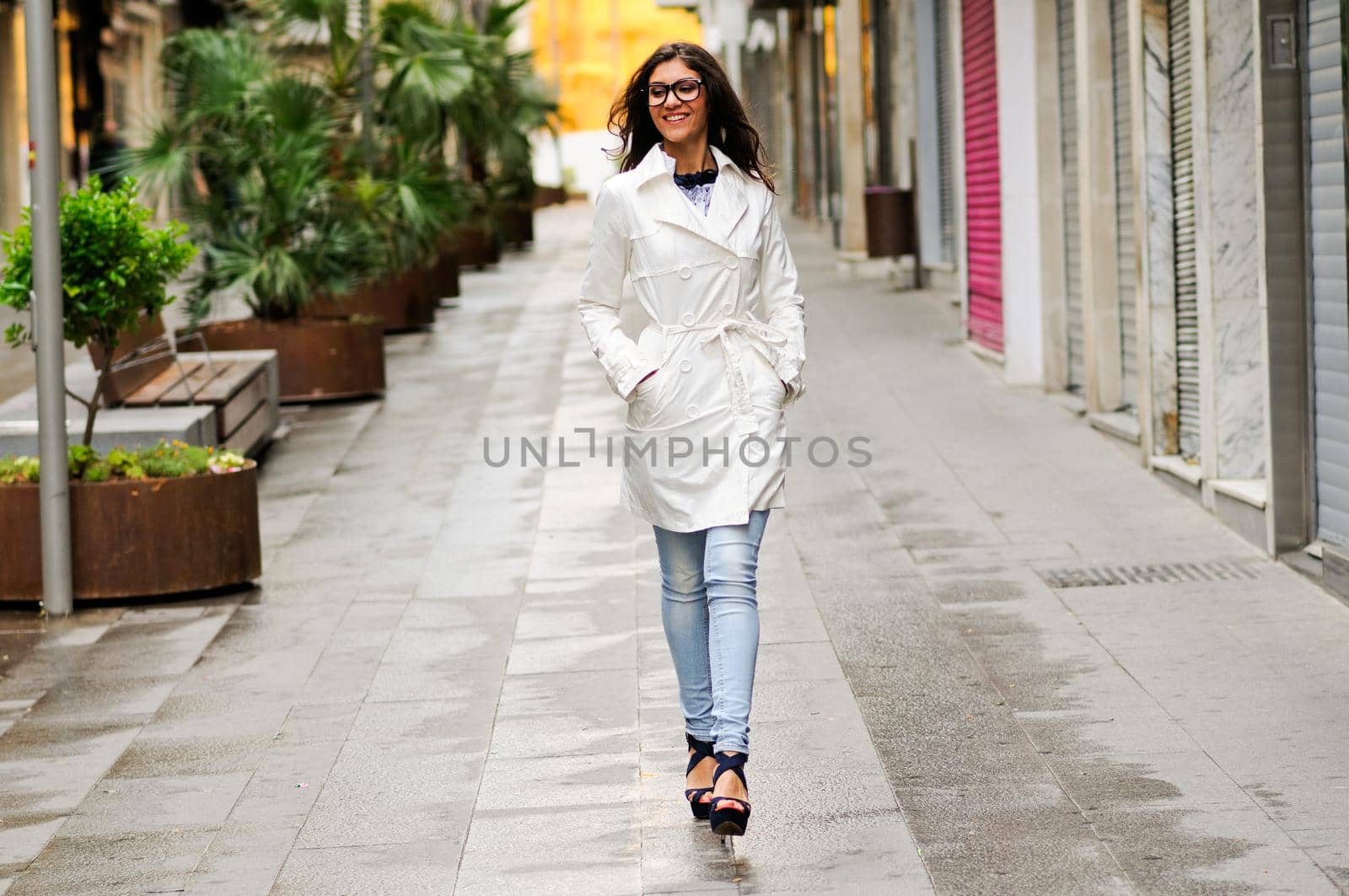 Beautiful woman with eyesglasses walking in urban background by javiindy