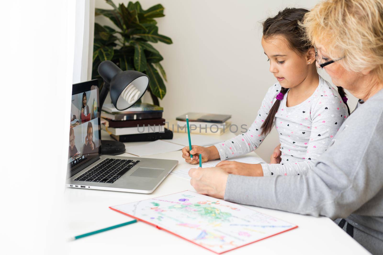 Helpful granny. Helpful loving granny assisting her cute granddaughter making homework