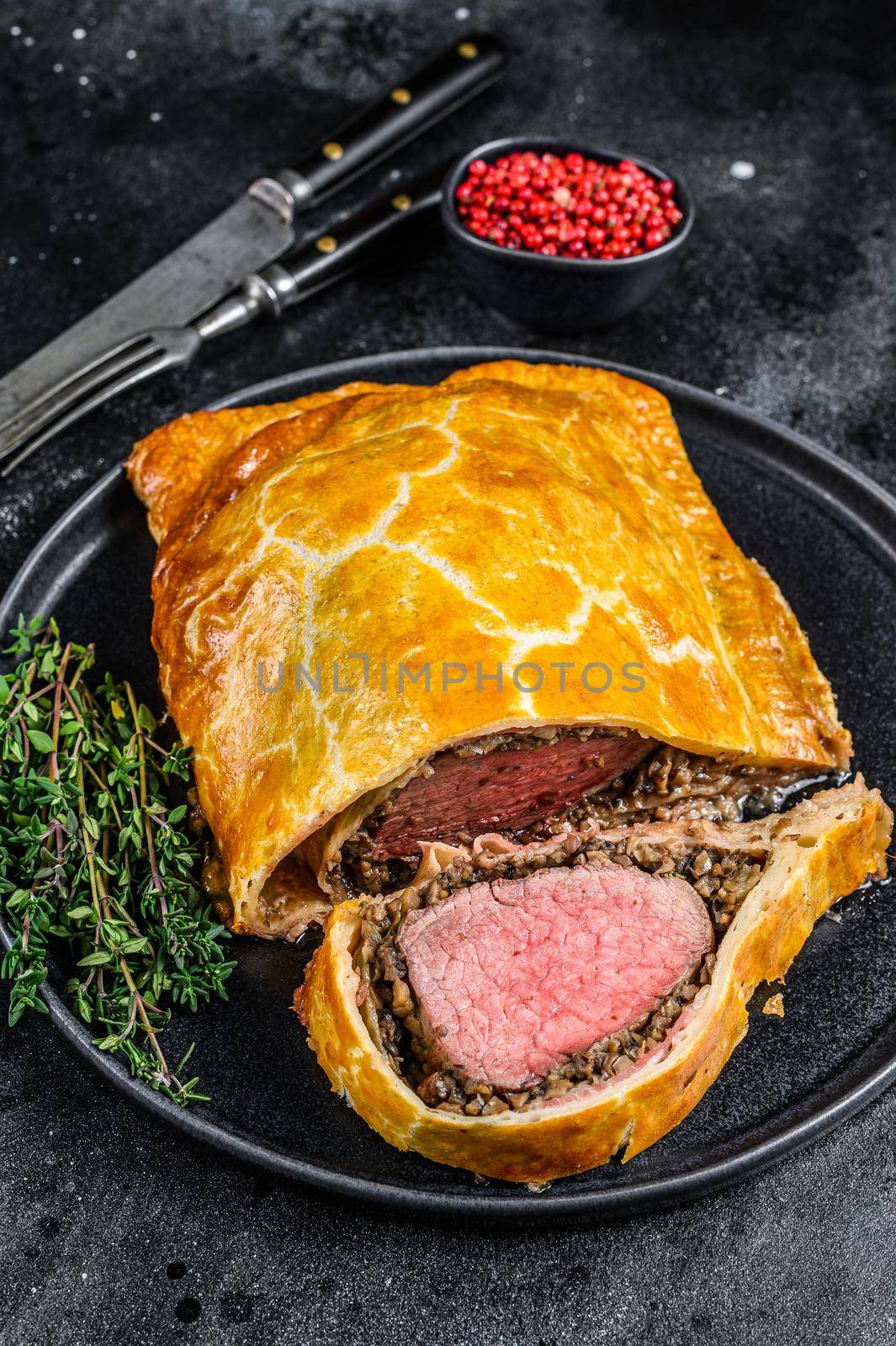 Beef Wellington classic steak dish with tenderloin meat on a plate. Black background. Top view by Composter