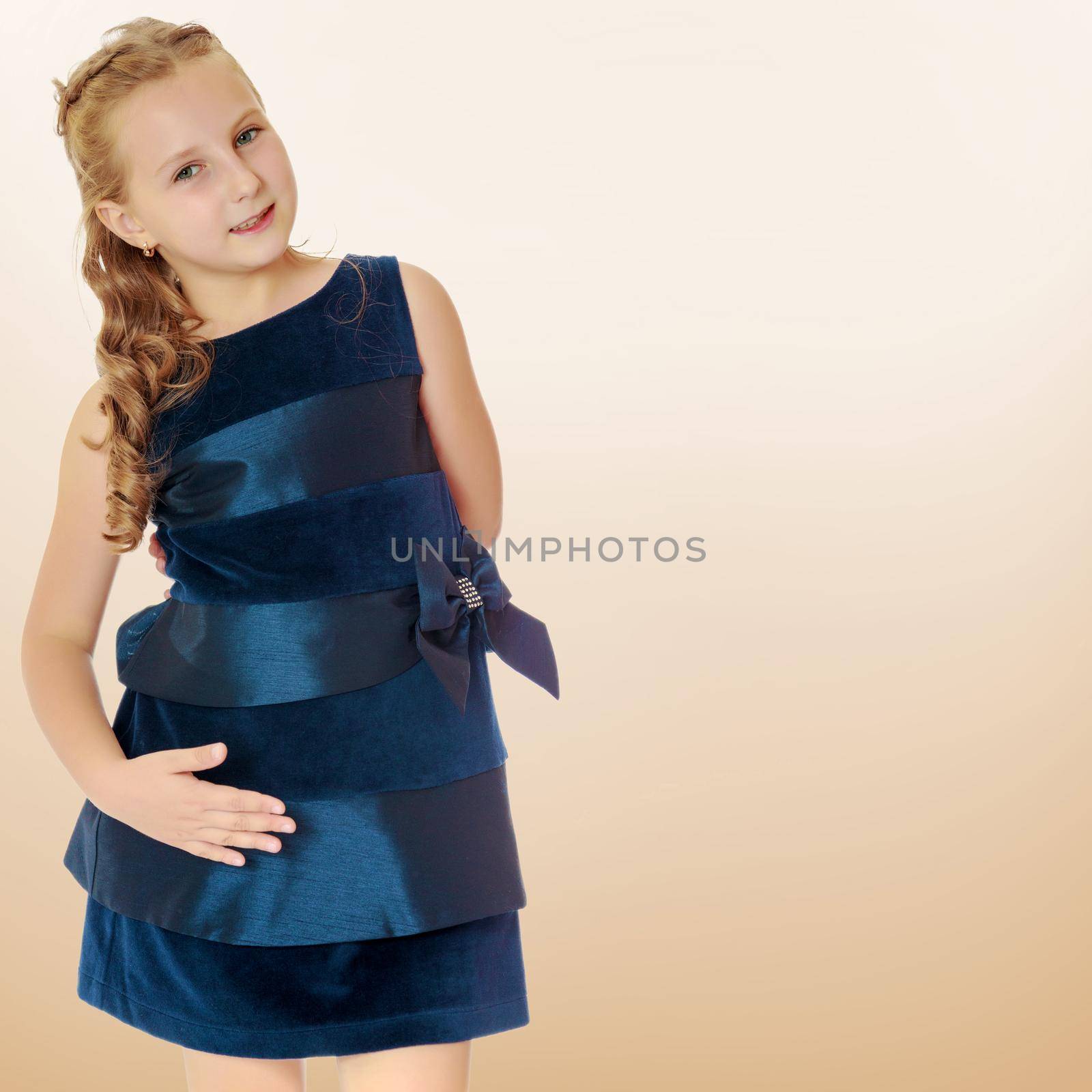Charming blond Caucasian girl in a dark blue dress, put his hand to his hip . close-up.On a brown gradient background.