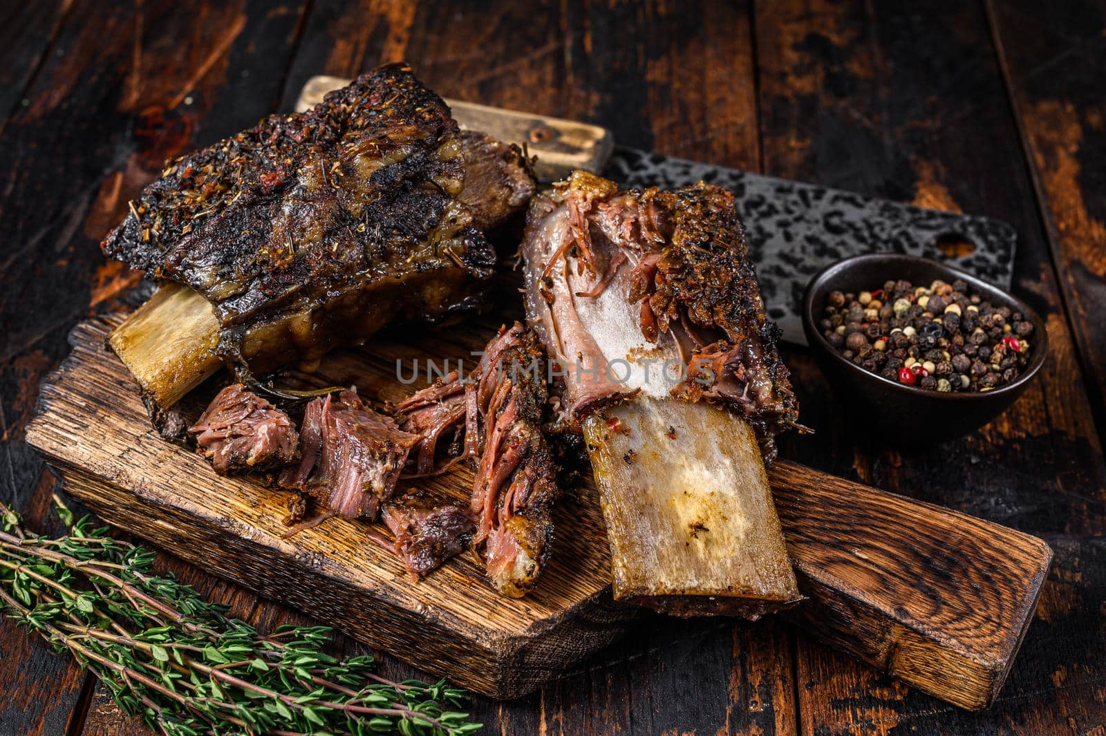 BBQ short chuck beef ribs with herbs and meat cleaver. Dark wooden background. Top view.