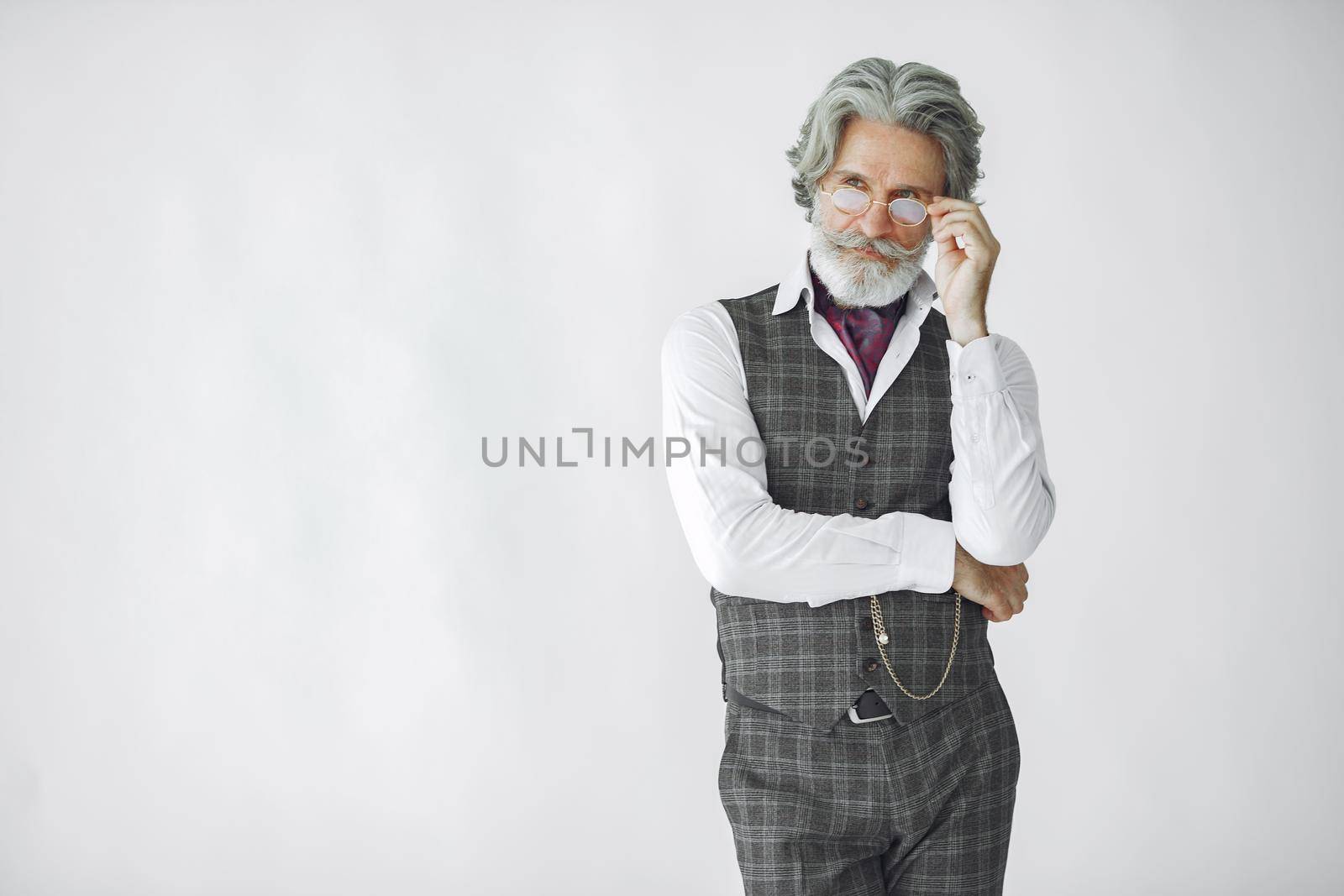 Close up portrait of grinning old-fashioned man. Elegant man in a studio. Grandfather with a clock.