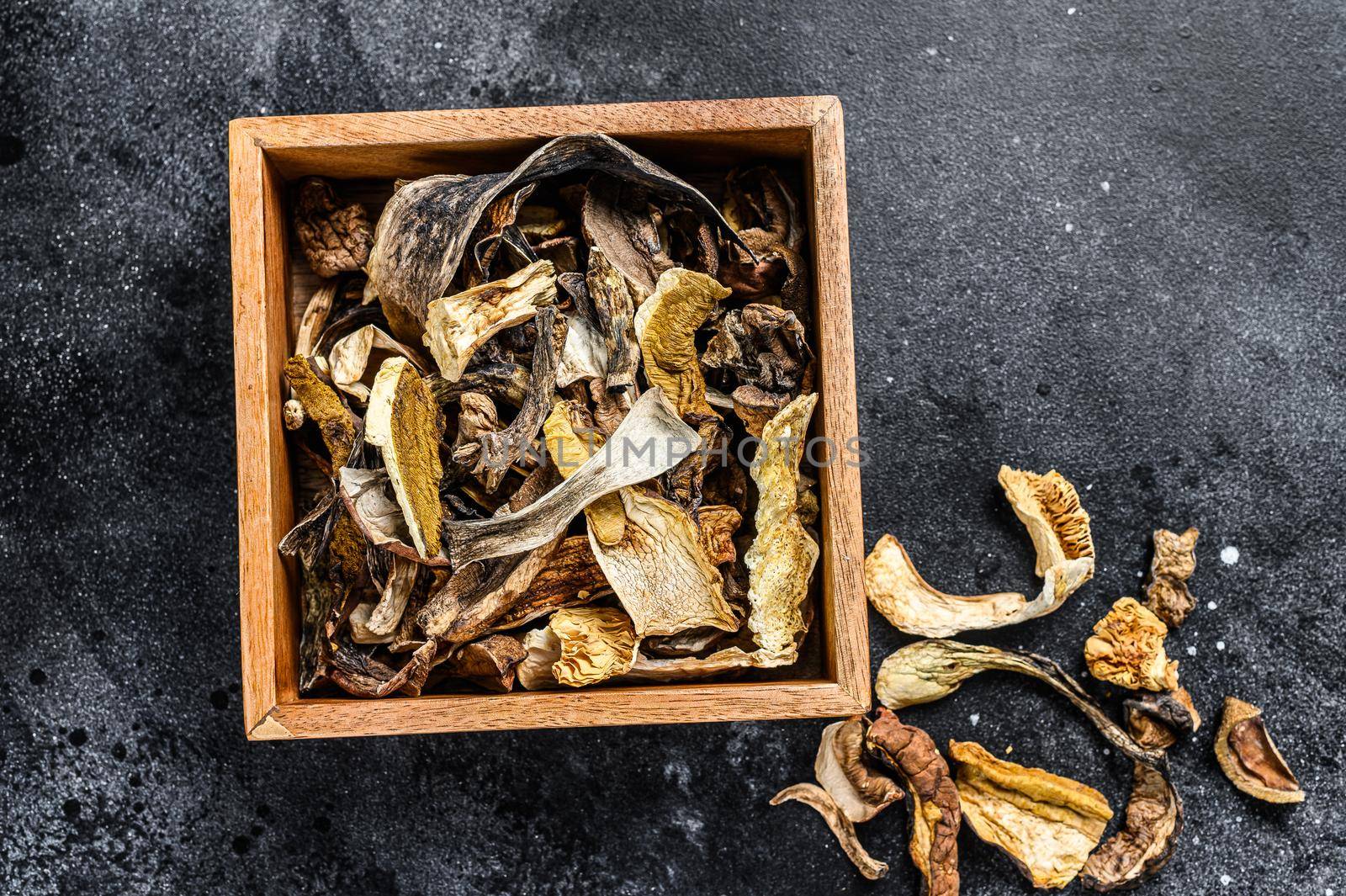 Boletus wild dried mushrooms in a wooden box. Black background. Top view.