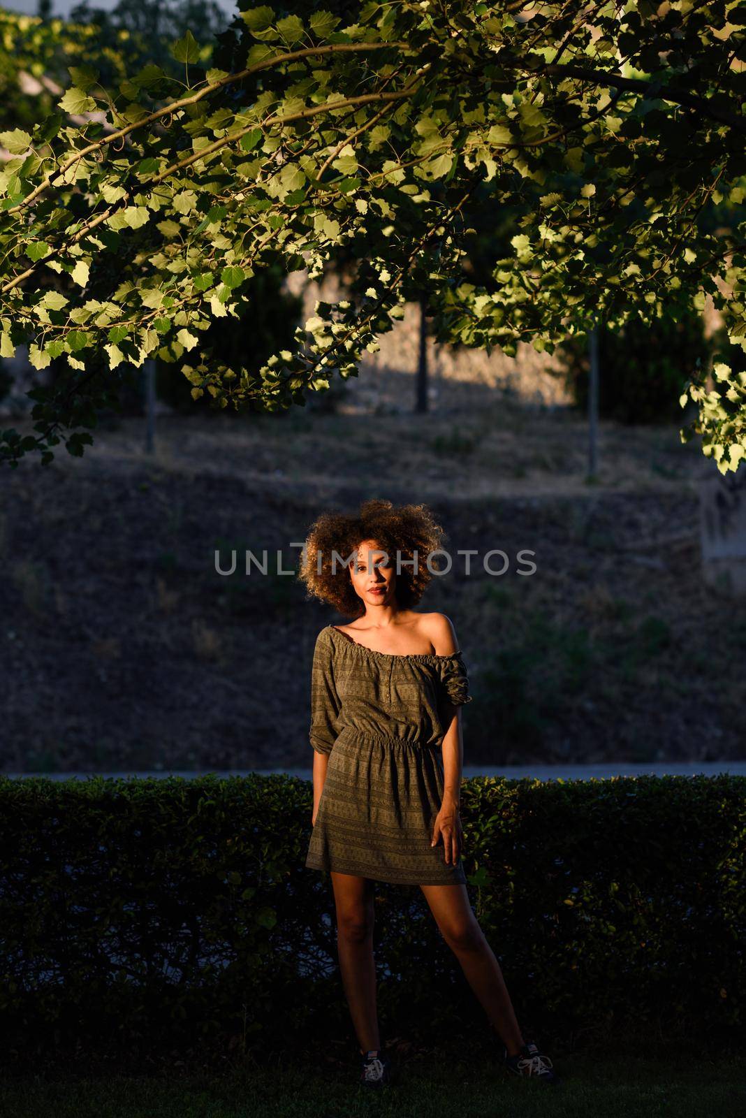 Young black woman with afro hairstyle standing in urban background. Mixed girl wearing casual clothes.