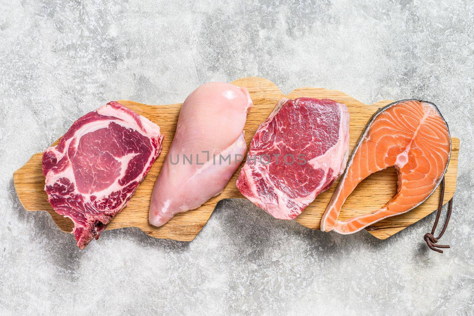 Mix of meat raw steaks salmon, beef, pork and chicken. Gray background. Top view by Composter