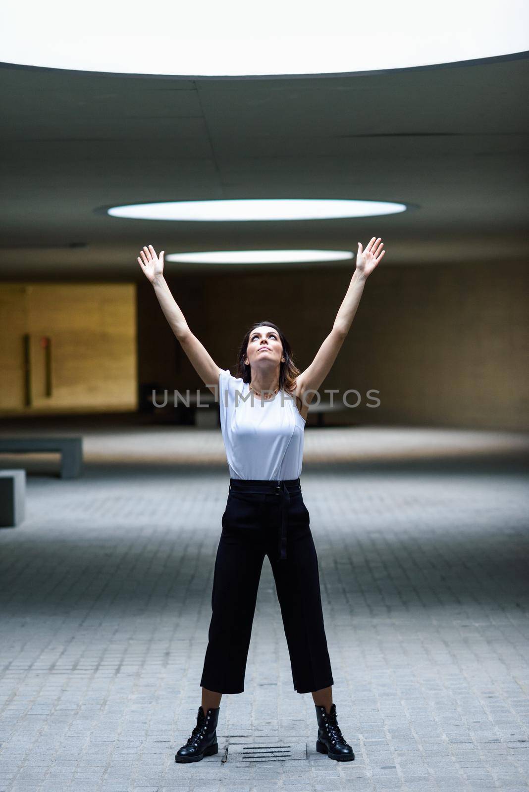 Beautiful brunette woman, model of fashion, posing in modern building with casual clothes.